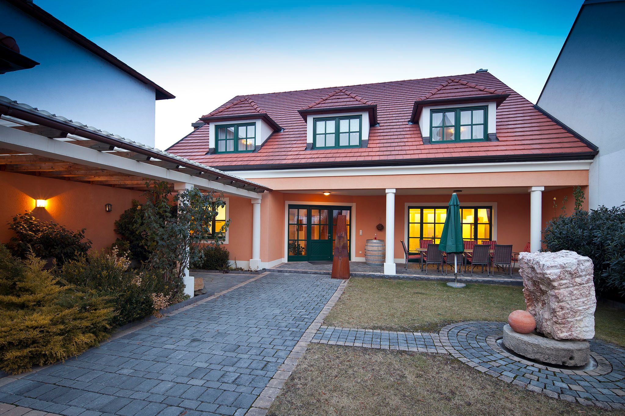 Gästehaus mit rotem Dach und Garten im Vordergrund.