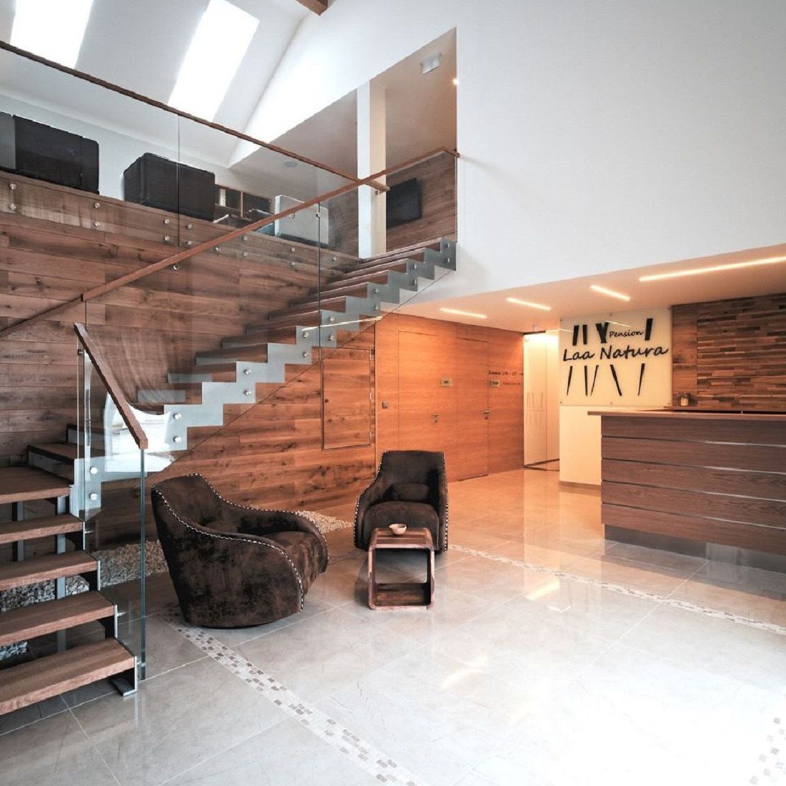 Moderner Eingangsbereich mit Holzverkleidung, Treppe und Rezeption.
