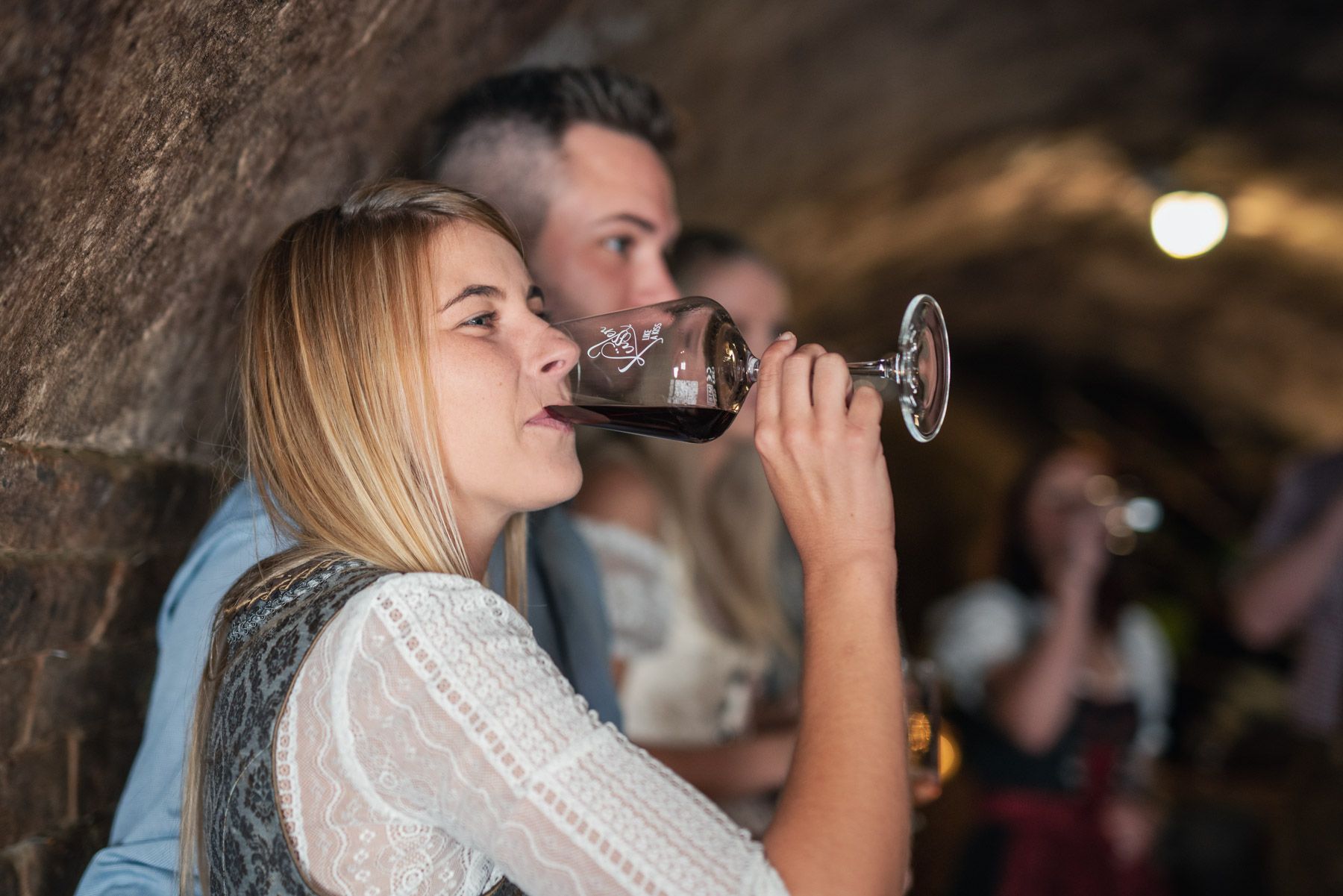 Frau trinkt Wein in einem Weinkeller.