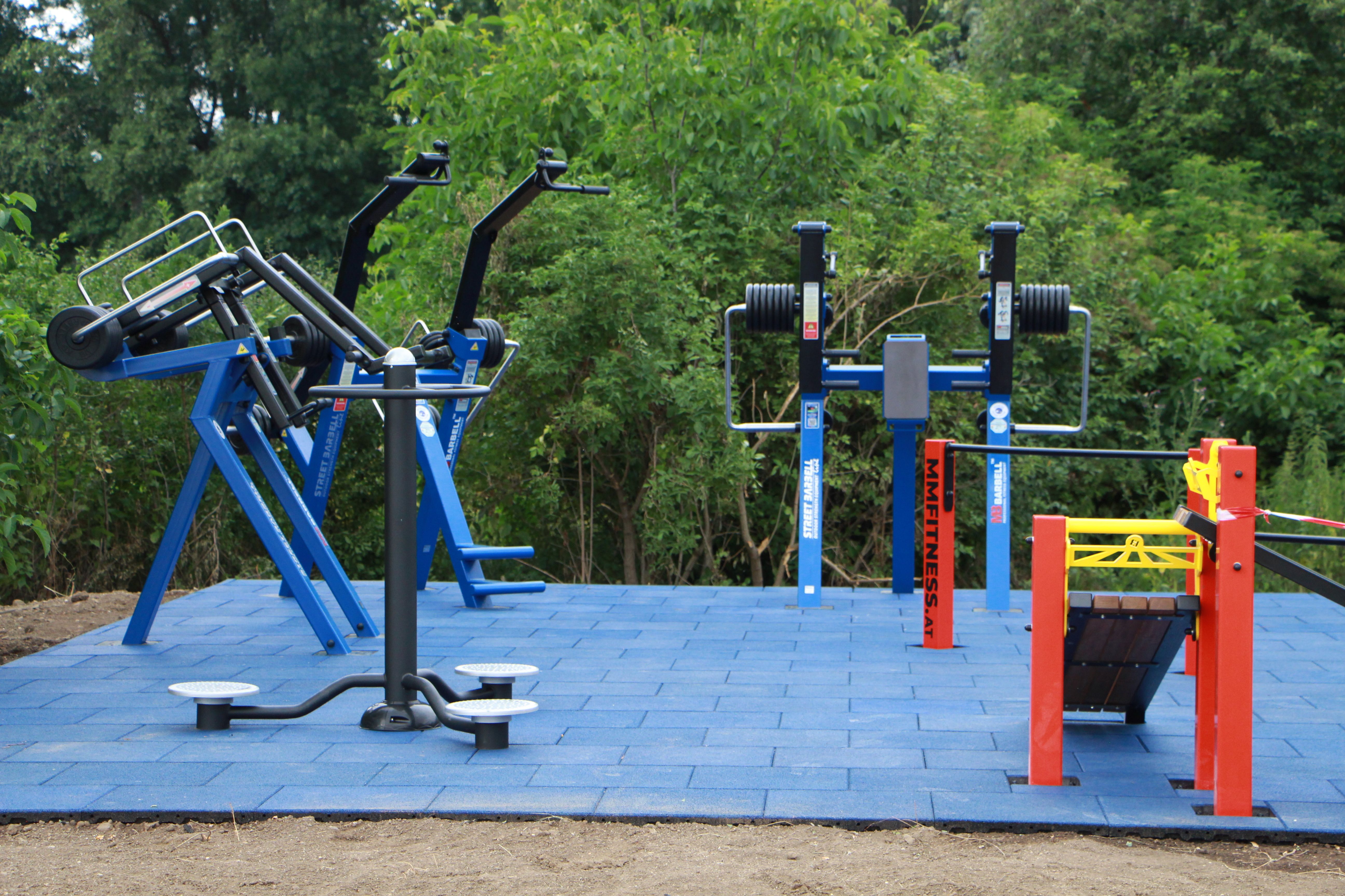 Venkovní fitness zařízení na modré venkovní dlažbě.
