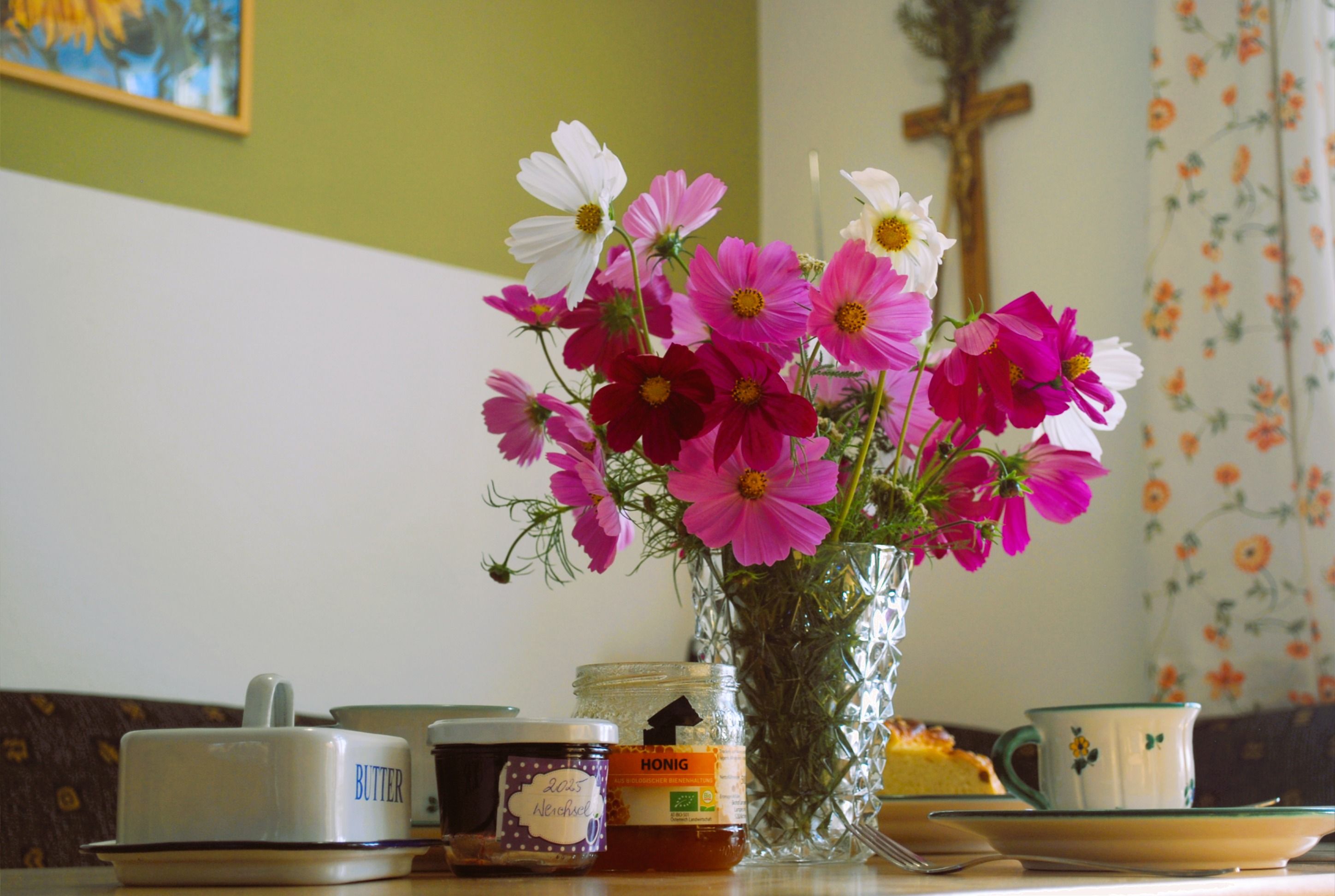 Ein Frühstückstisch mit Blumenstrauß, Marmelade, Honig und Geschirr.
