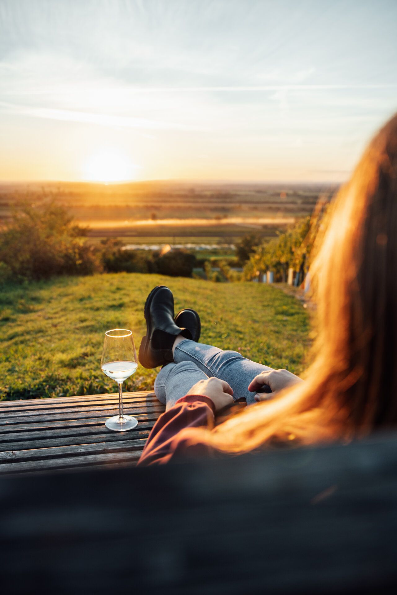 Genießen Sie den atemberaubenden Sonnenuntergang über den sanften Hügeln, während Sie in einem Weingarten entspannen. Ein Glas erlesener Wein in der Hand und die warmen Farben des Himmels schaffen eine unvergessliche Atmosphäre der Ruhe und des Genusses.