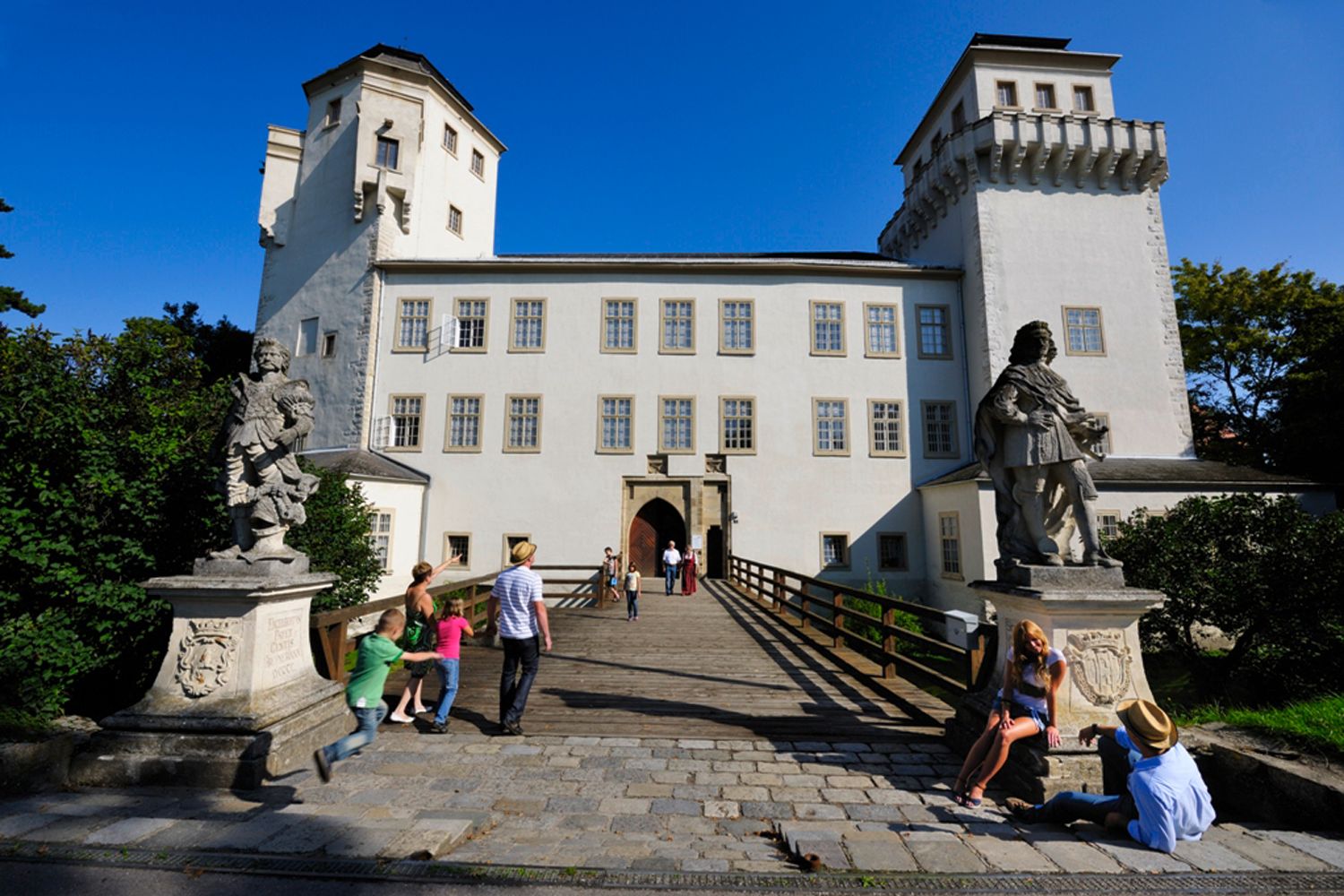 Schloss Asparn/Zaya mit Besuchern und Statuen im Vordergrund.