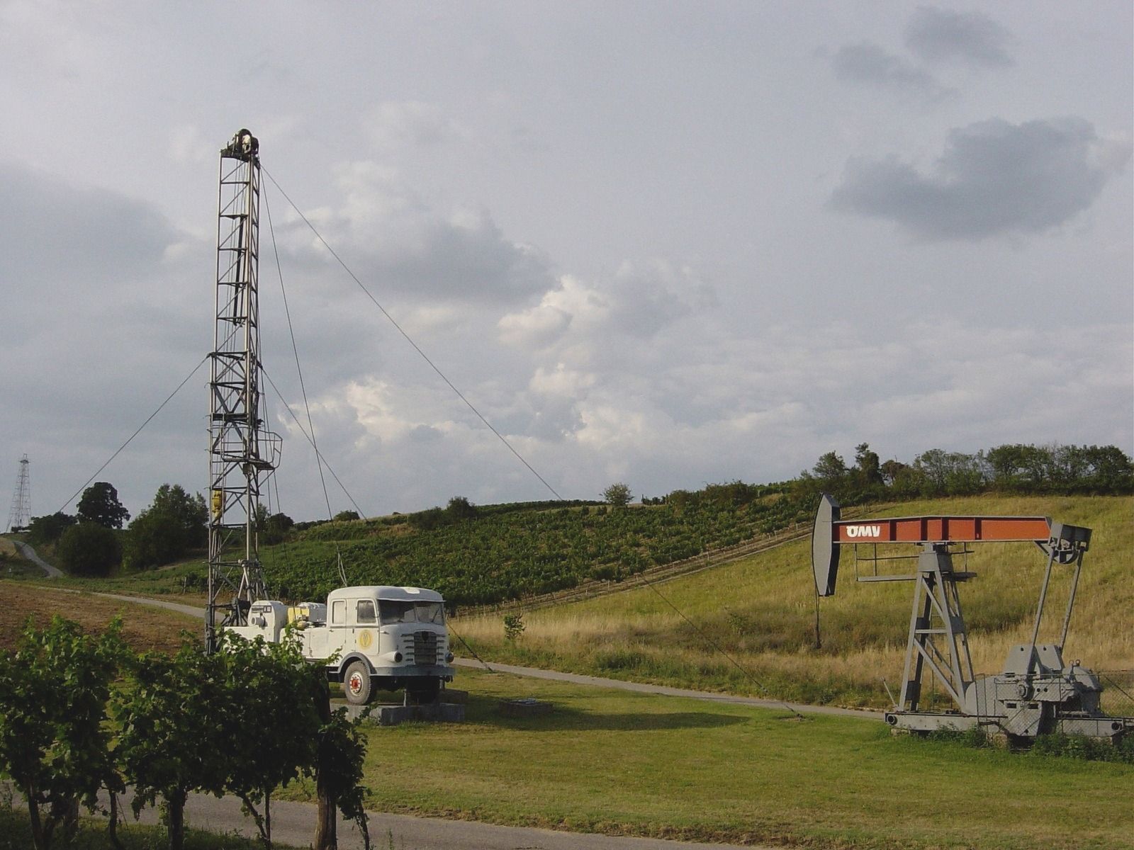 Ölförderpumpe und Bohrturm in ländlicher Umgebung.