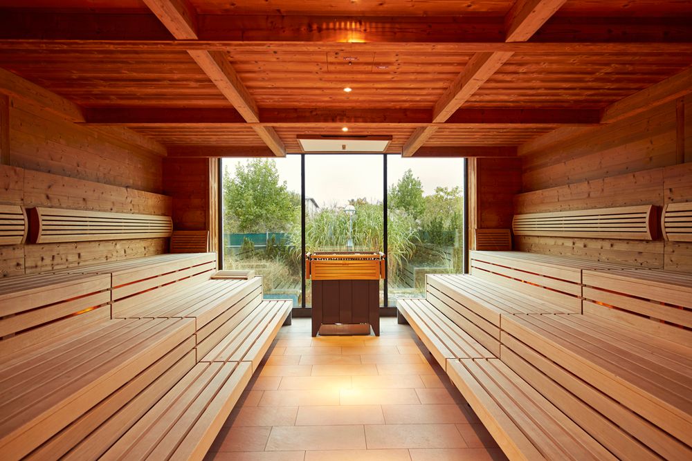 Interior view of a sauna with wooden benches and a window with a view of the greenery.