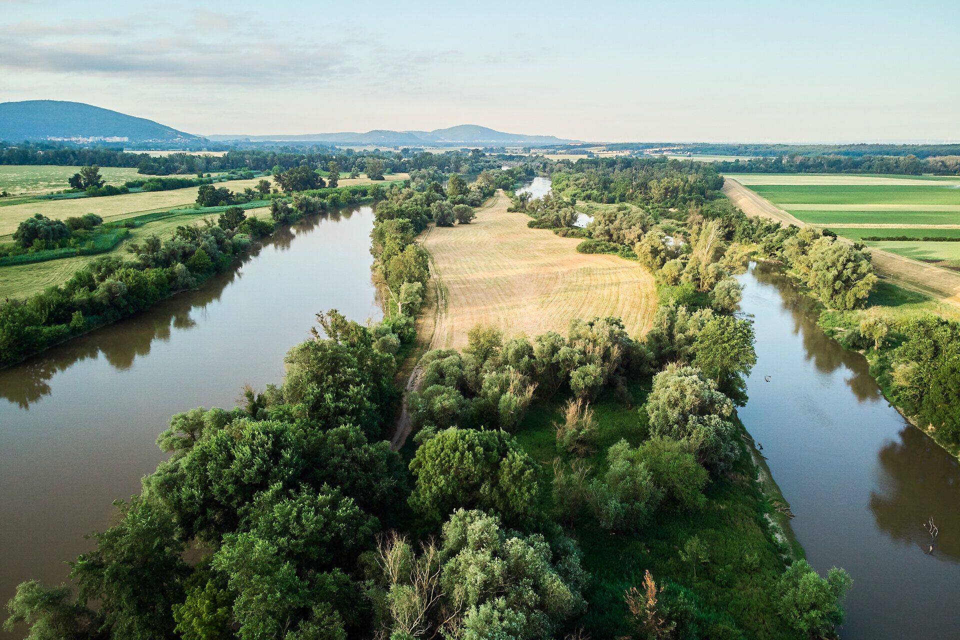 Die sanften Wellen des Flusses umarmen die üppigen Uferlandschaften, während die Sonne sanft über die Felder strahlt. Hier, wo die Natur in voller Blüte steht, lädt die malerische Umgebung zu unvergesslichen Erlebnissen ein.