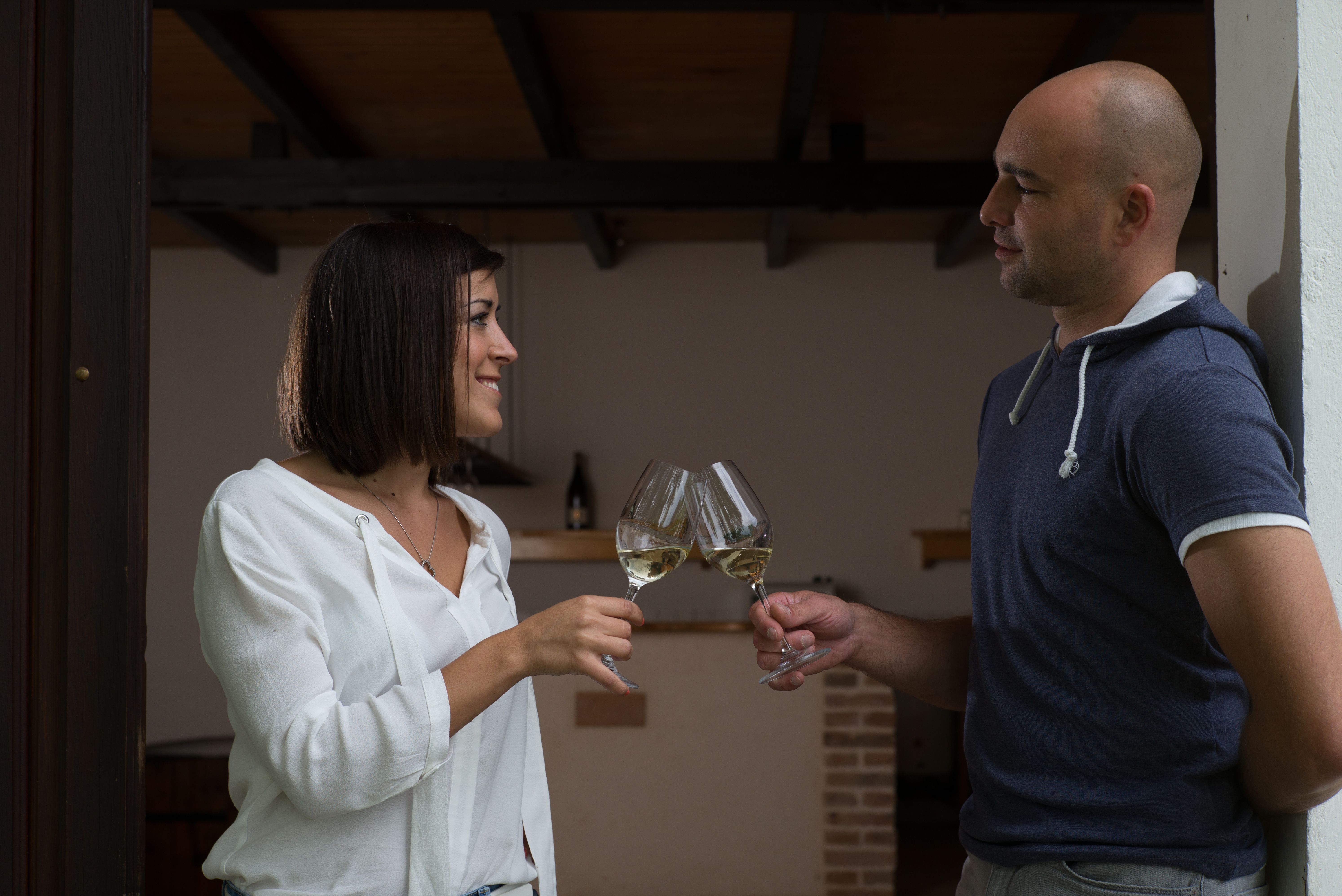 Zwei Personen stoßen mit Weingläsern an.