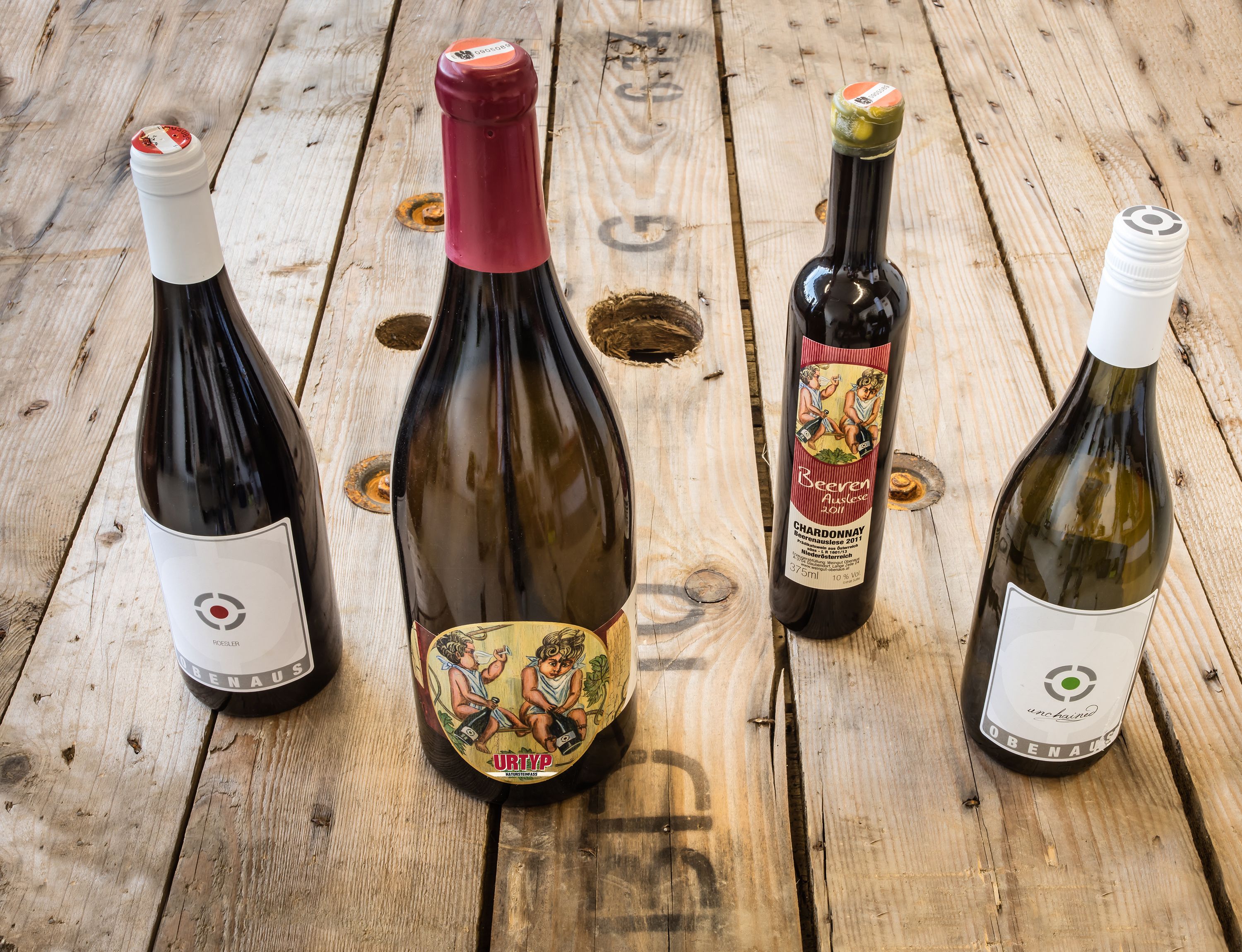 Four bottles of wine on a wooden table.