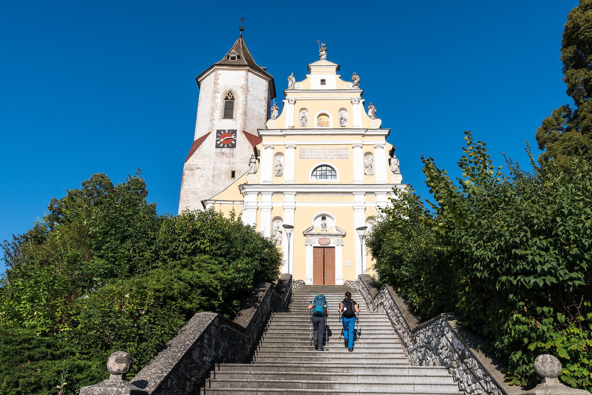 Die majestätische Fassade des historischen Gebäudes strahlt im Sonnenlicht und lädt zu einem Besuch ein. Die steilen Treppen, umgeben von üppigem Grün, führen direkt zu diesem beeindruckenden Ort, der Geschichte und Kultur vereint. Hier erleben Besucher die Schönheit der Natur und die Ruhe der Umgebung.