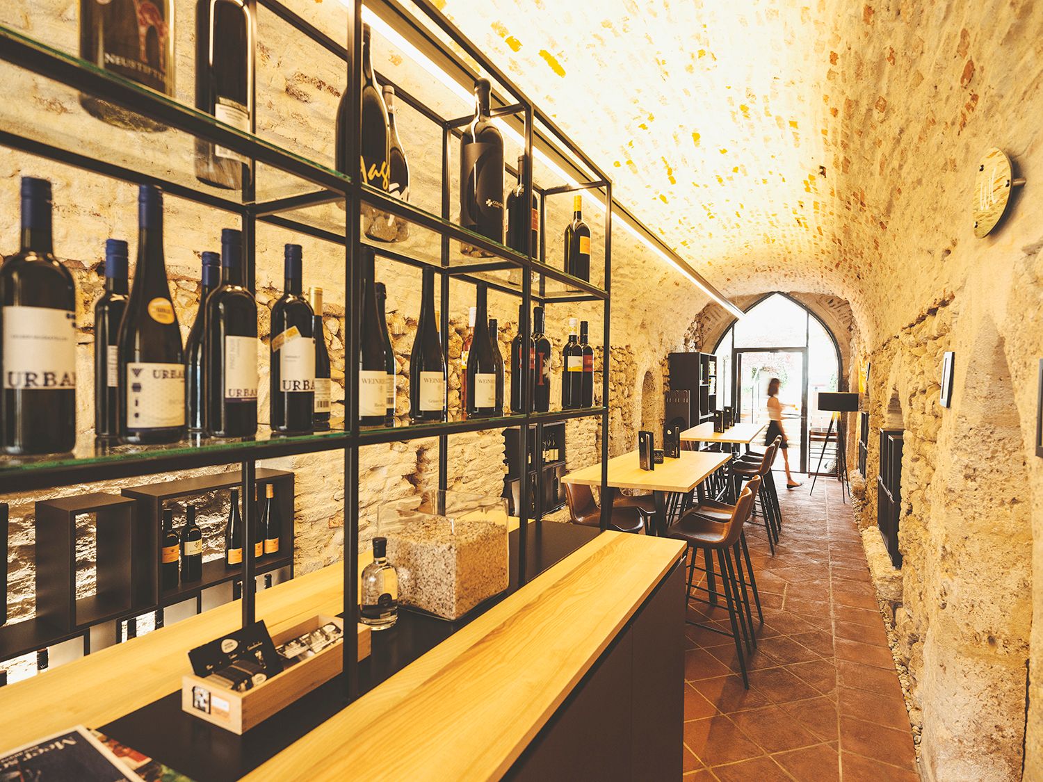 Weinkeller mit Flaschenregalen und Tischen in einem Gewölbe.