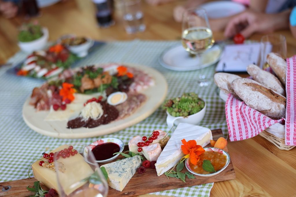 Ein gedeckter Tisch mit Käseplatte, Brot, Aufschnitt und Wein.