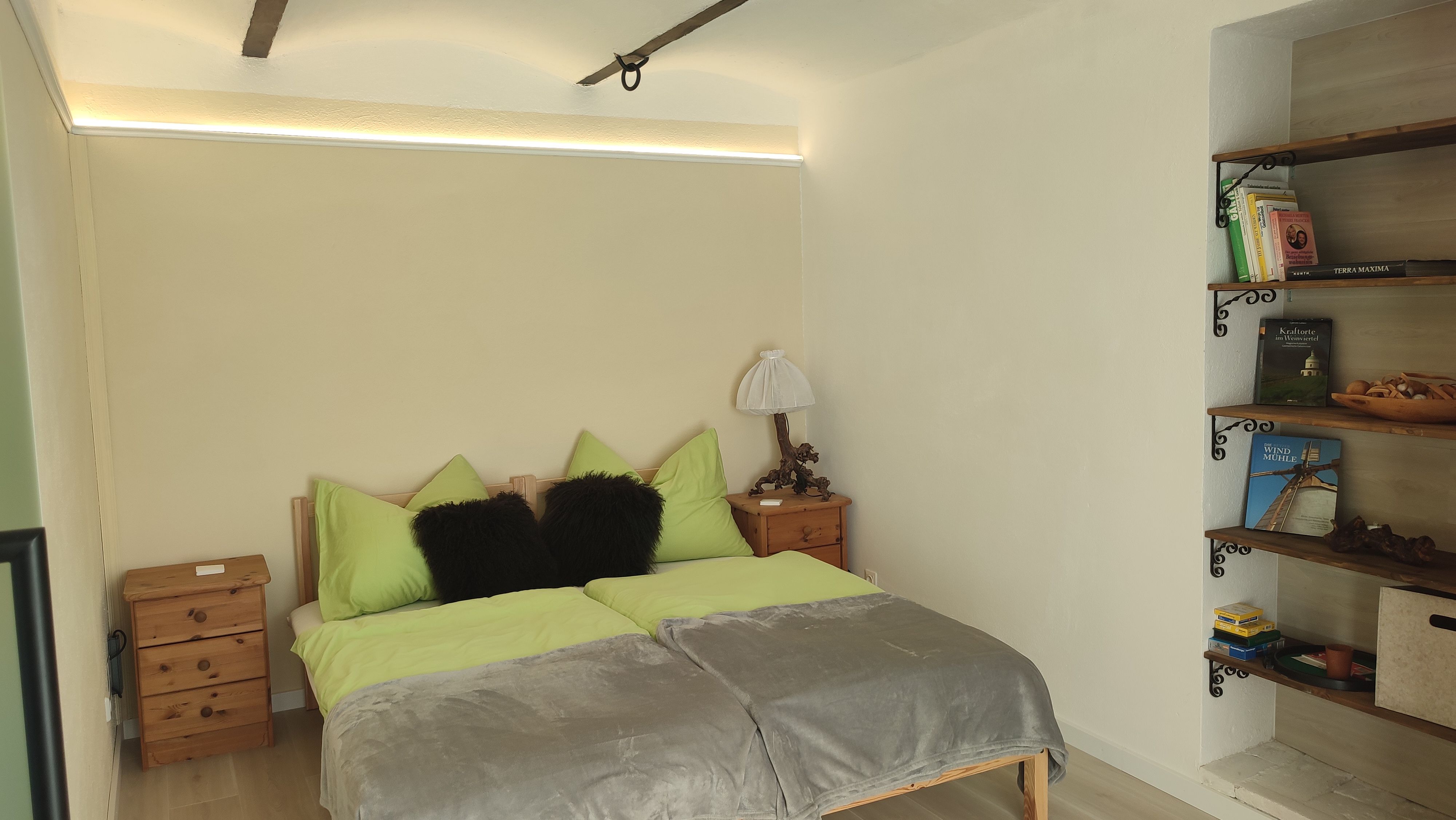 Gemütliches Schlafzimmer mit Doppelbett, Nachttischen und einem Regal mit Büchern.