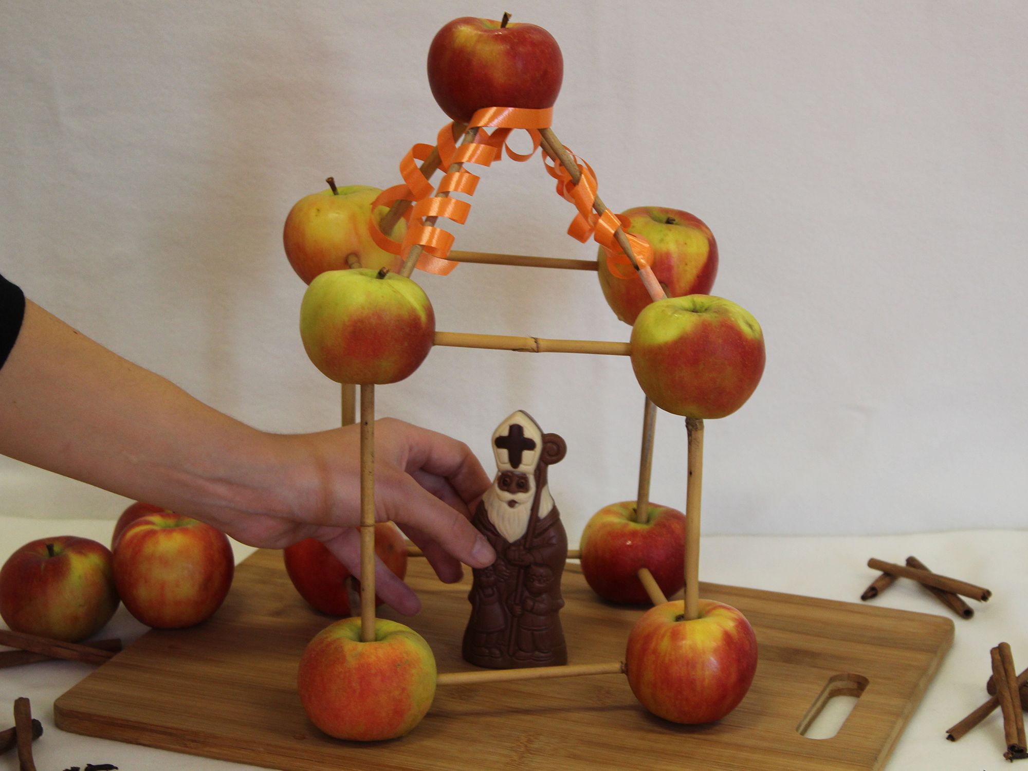 Ein Schokoladen-Nikolaus wird in ein Haus aus Äpfeln gestellt.