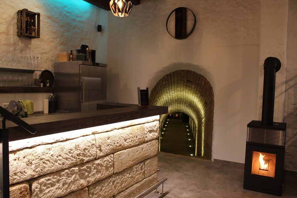 Innenansicht einer Vinothek mit Theke, Kamin und beleuchtetem Tunnel.