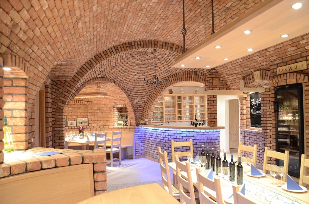 Cozy wine cellar with brick walls, laid table and wine bottles.