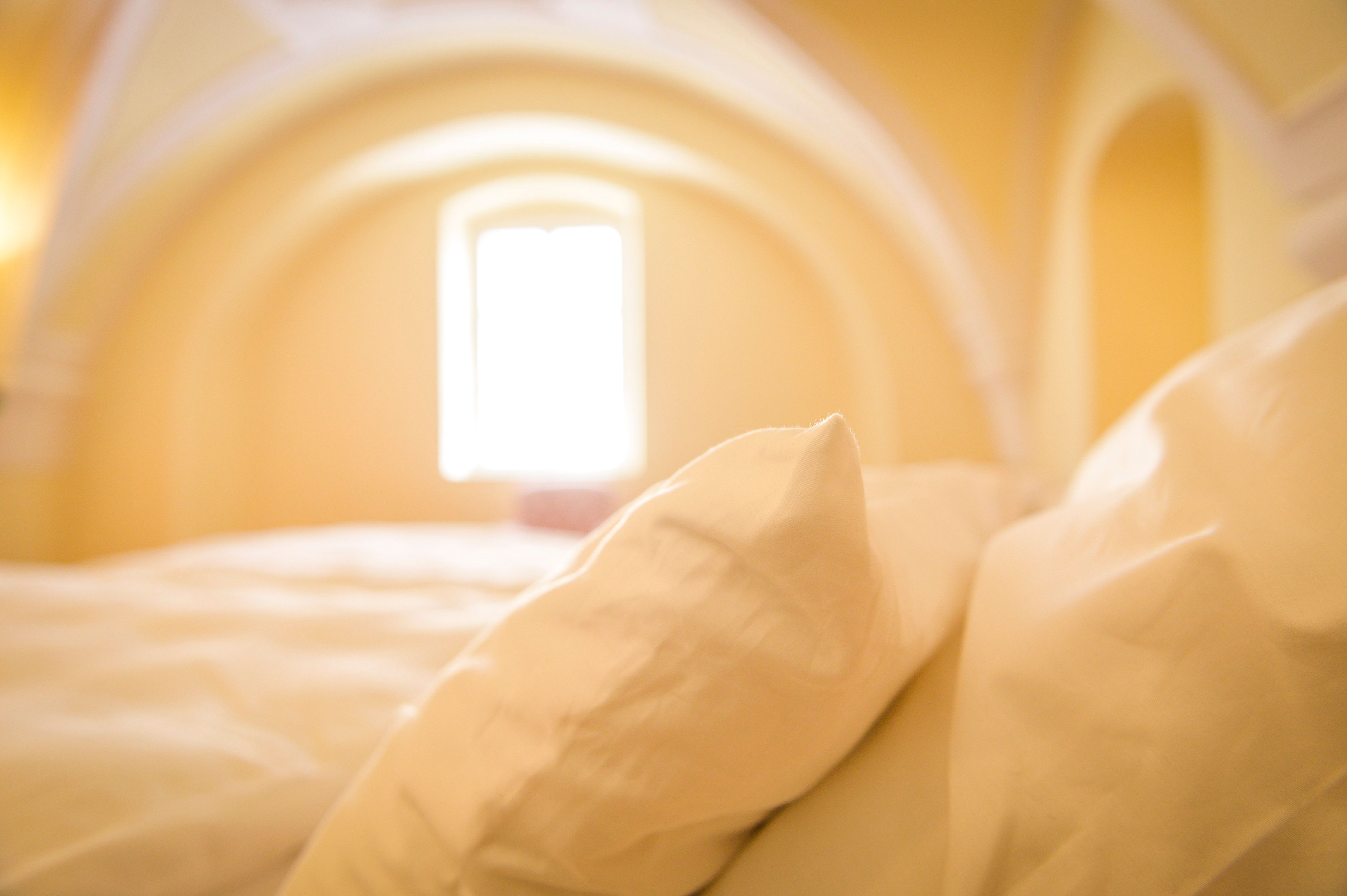 Nahaufnahme von Kissen auf einem Bett in einem Raum mit gewölbter Decke und Fenster.
