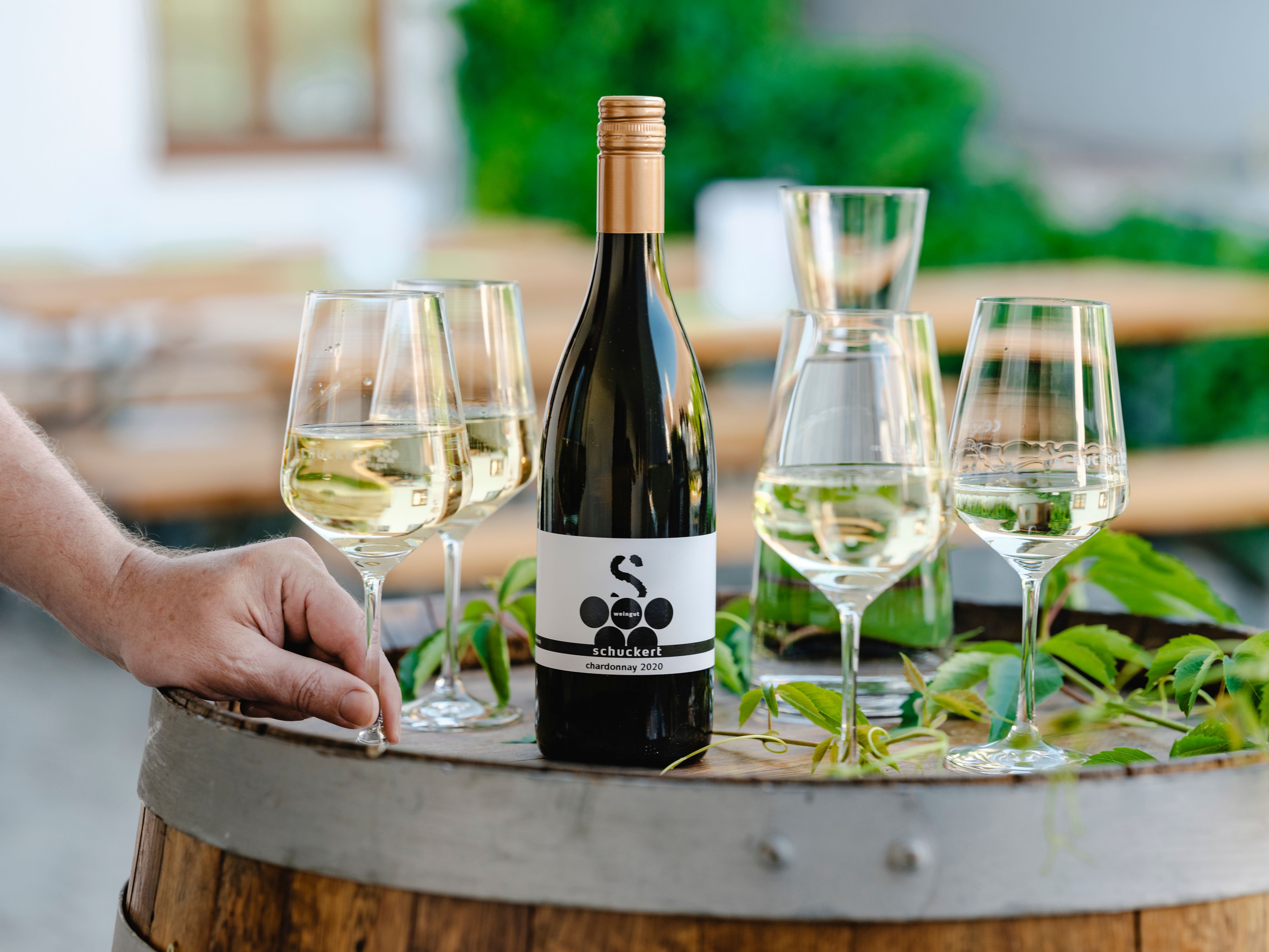 Wine bottle and glasses on a wine barrel outdoors.