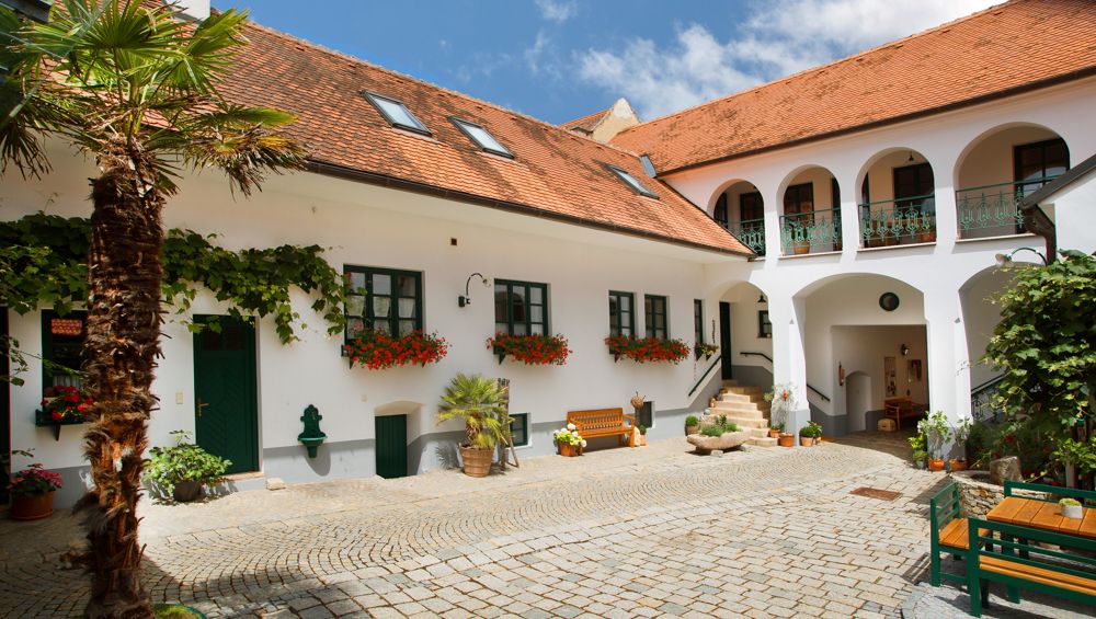 Ein traditioneller österreichischer Innenhof mit weißen Gebäuden, roten Ziegeldächern und Blumen.