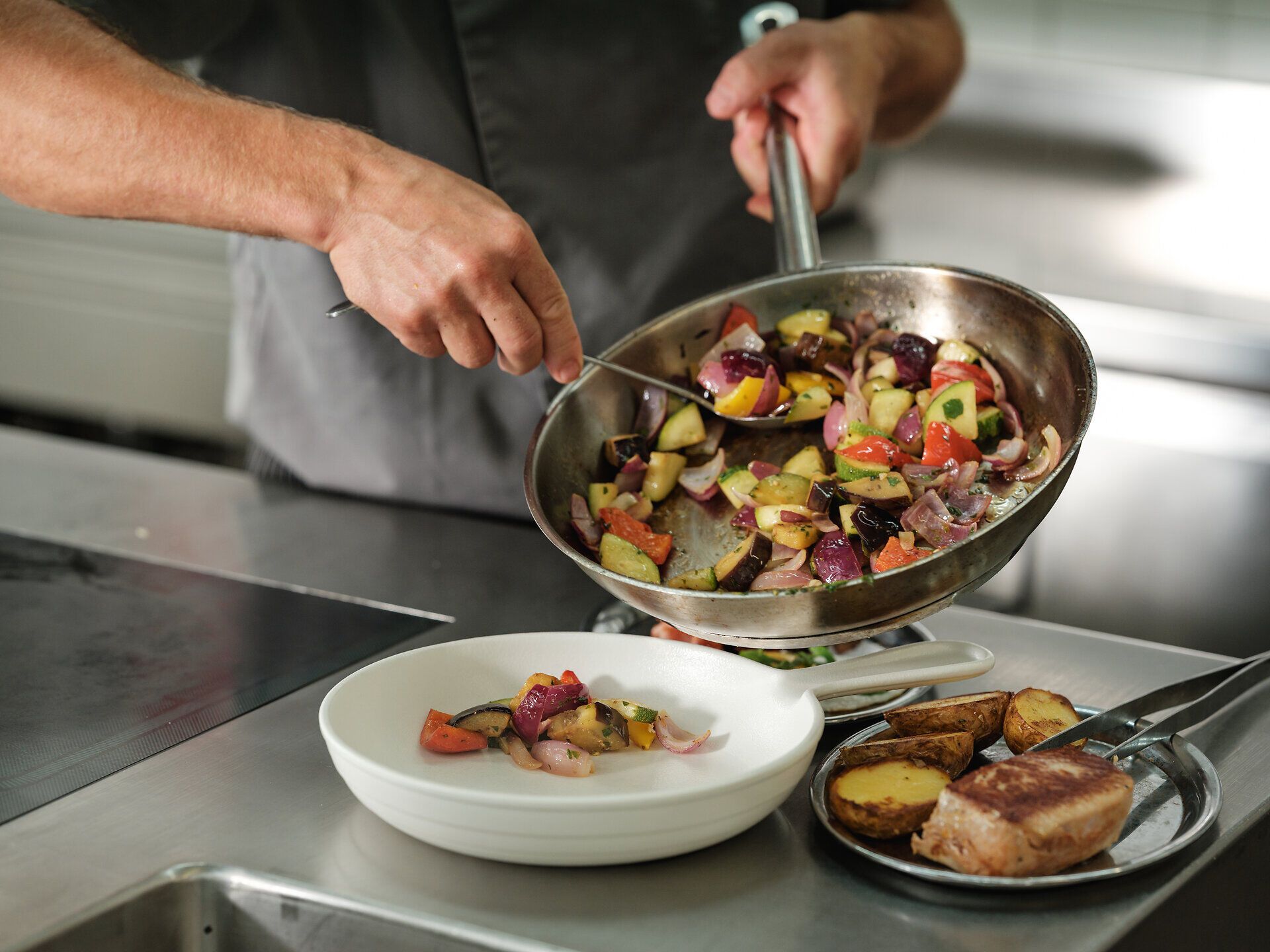 In einem einladenden Restaurant wird eine köstliche Mischung aus frischem Gemüse und zarten Fleischstücken zubereitet. Die Farben der Zutaten strahlen in der warmen Küchenszene und versprechen ein unvergessliches kulinarisches Erlebnis. Hier wird die Leidenschaft für die regionale Küche lebendig.