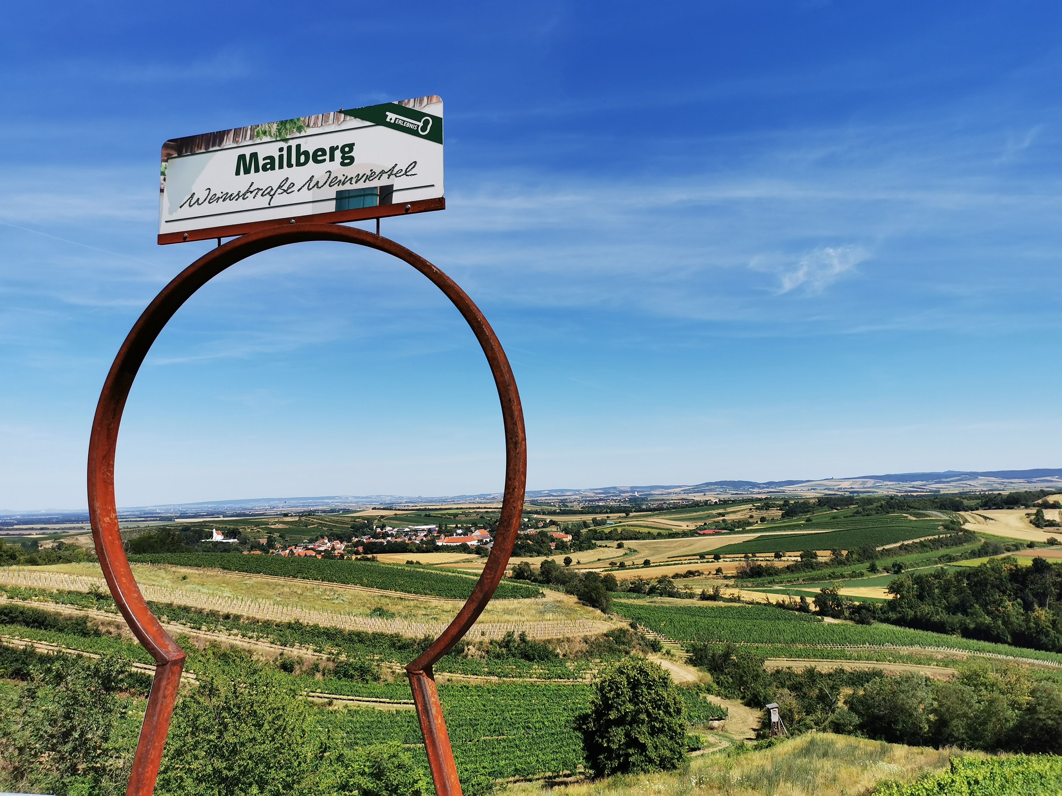 Landscape with vineyards and a sign with the inscription 'Mailberg Wein Road Weinviertel'.