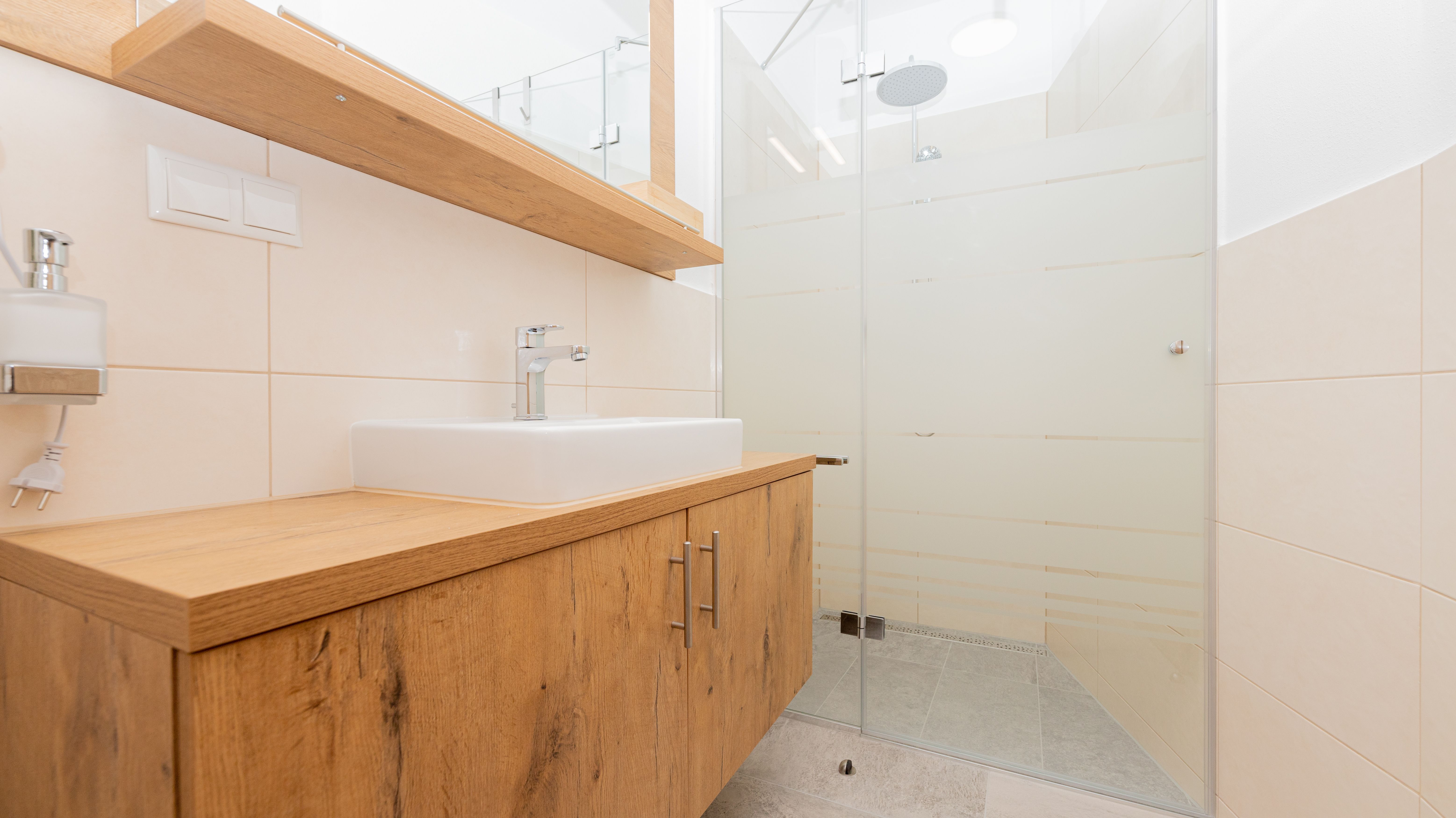 Modernes Badezimmer mit Holzwaschtisch und Glasdusche.