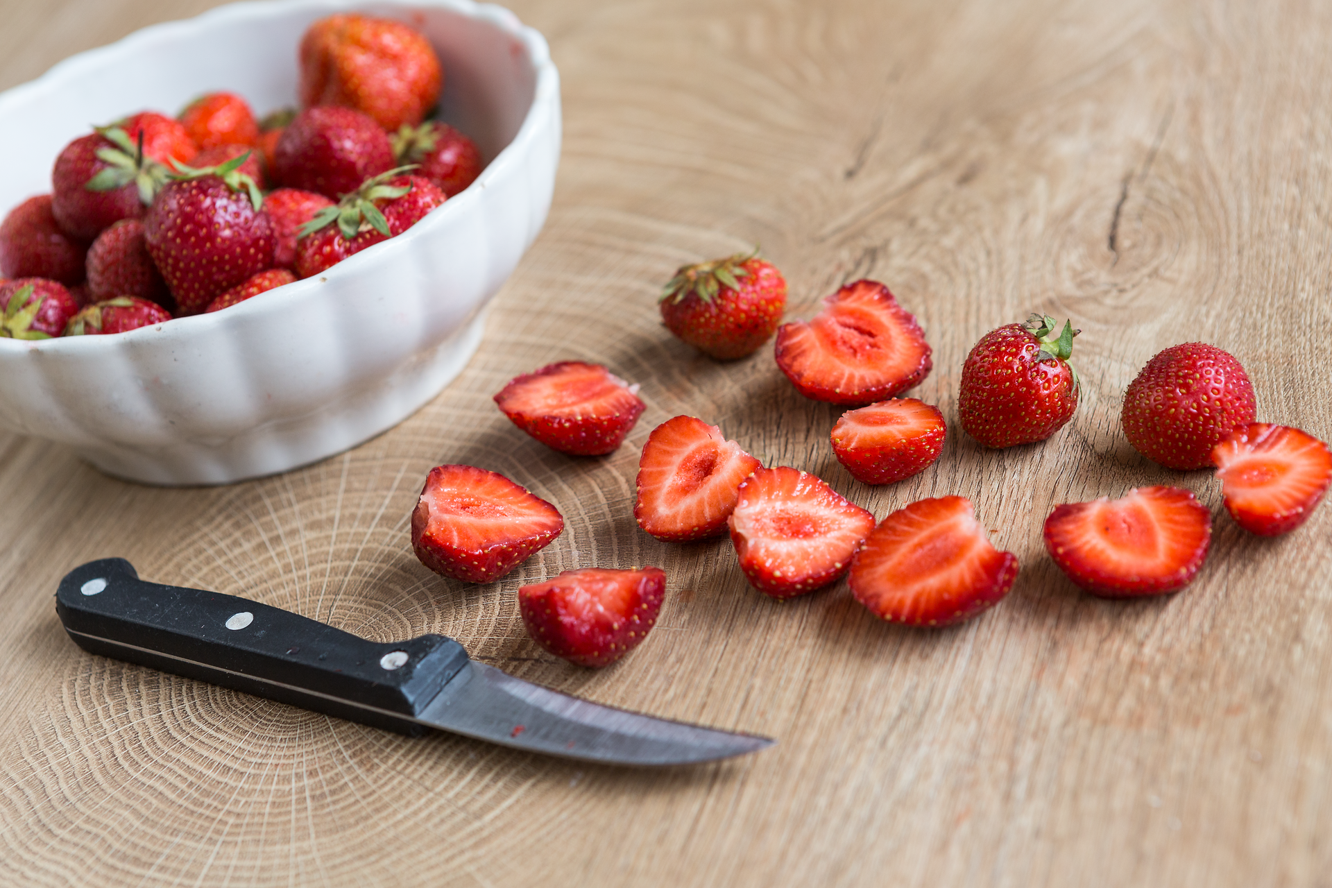 Frische, saftige Erdbeeren liegen verlockend auf einem rustikalen Holztisch, während eine Schüssel voller reifer Früchte im Hintergrund strahlt. Der Duft der süßen Beeren erfüllt die Luft und lädt dazu ein, die köstlichen Aromen der Weinviertler Küche zu entdecken.
