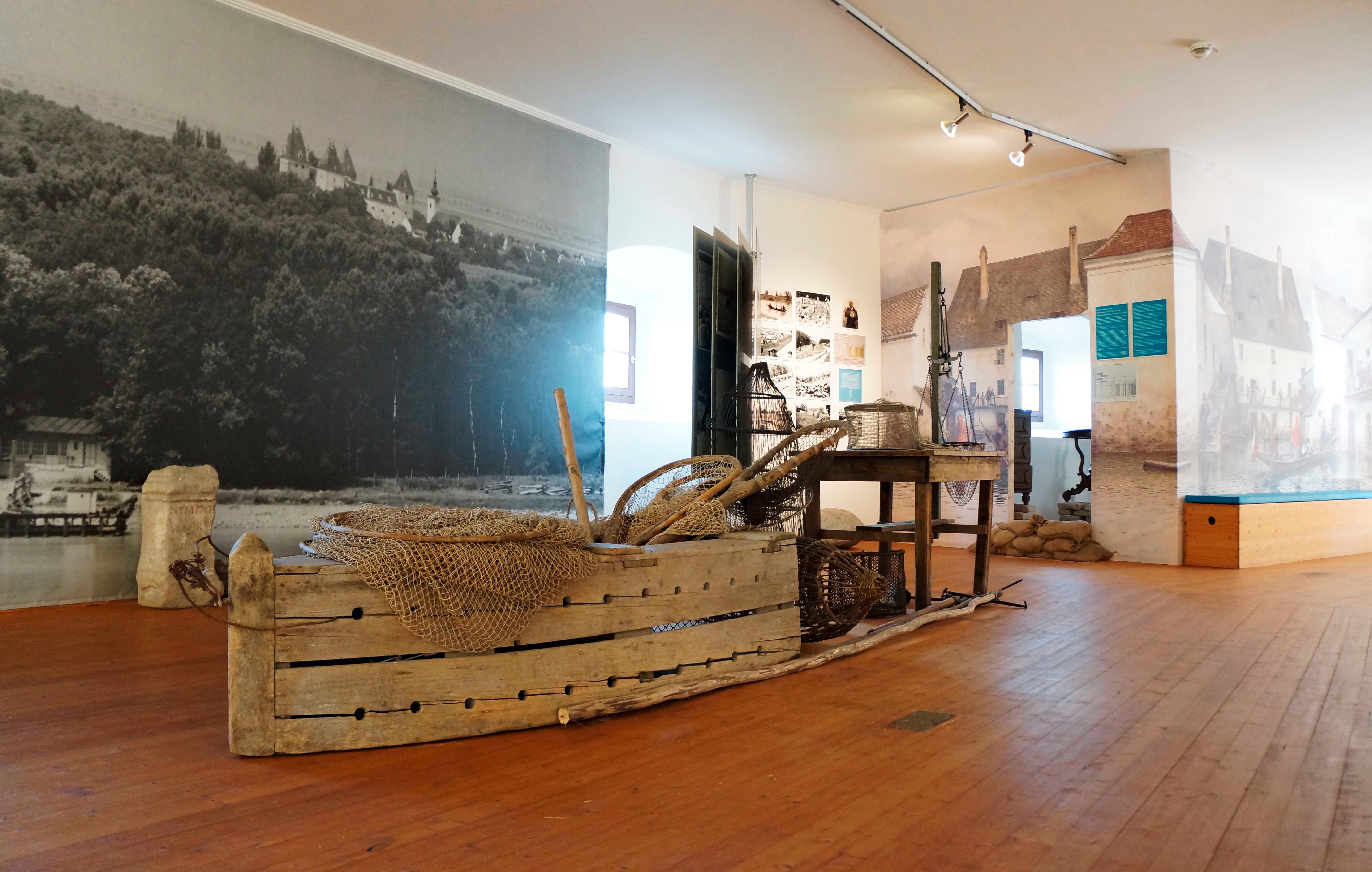 Innenansicht eines Museums mit historischen Fischereigeräten und Wandbildern.