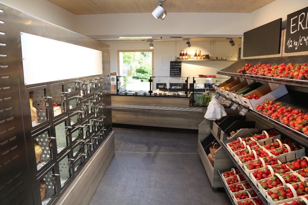 Innenansicht eines Hofladens mit Verkaufsautomaten und frischen Erdbeeren.