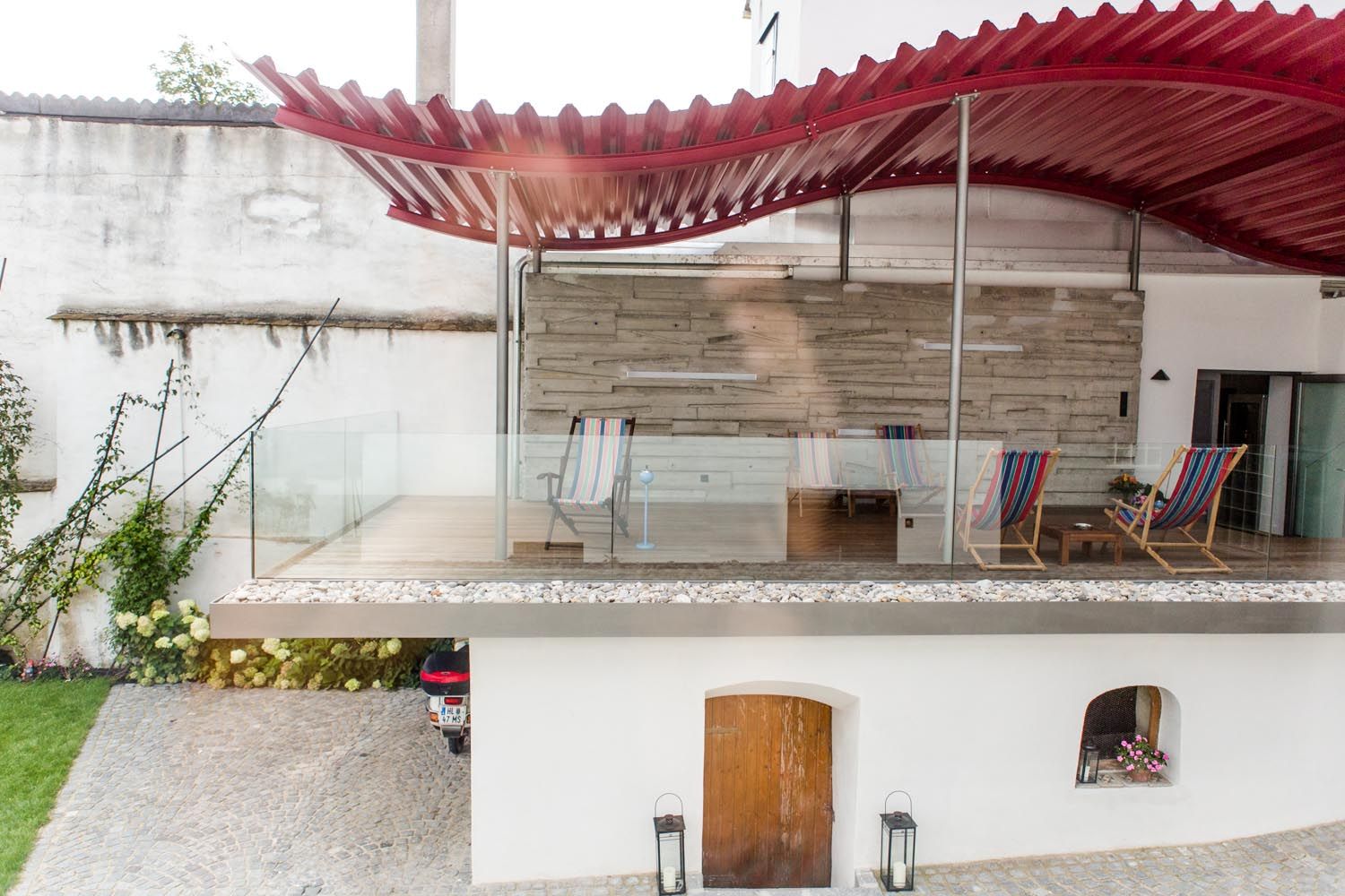 Terrasse mit roten Dach und Liegestühlen in einem Gästehaus.