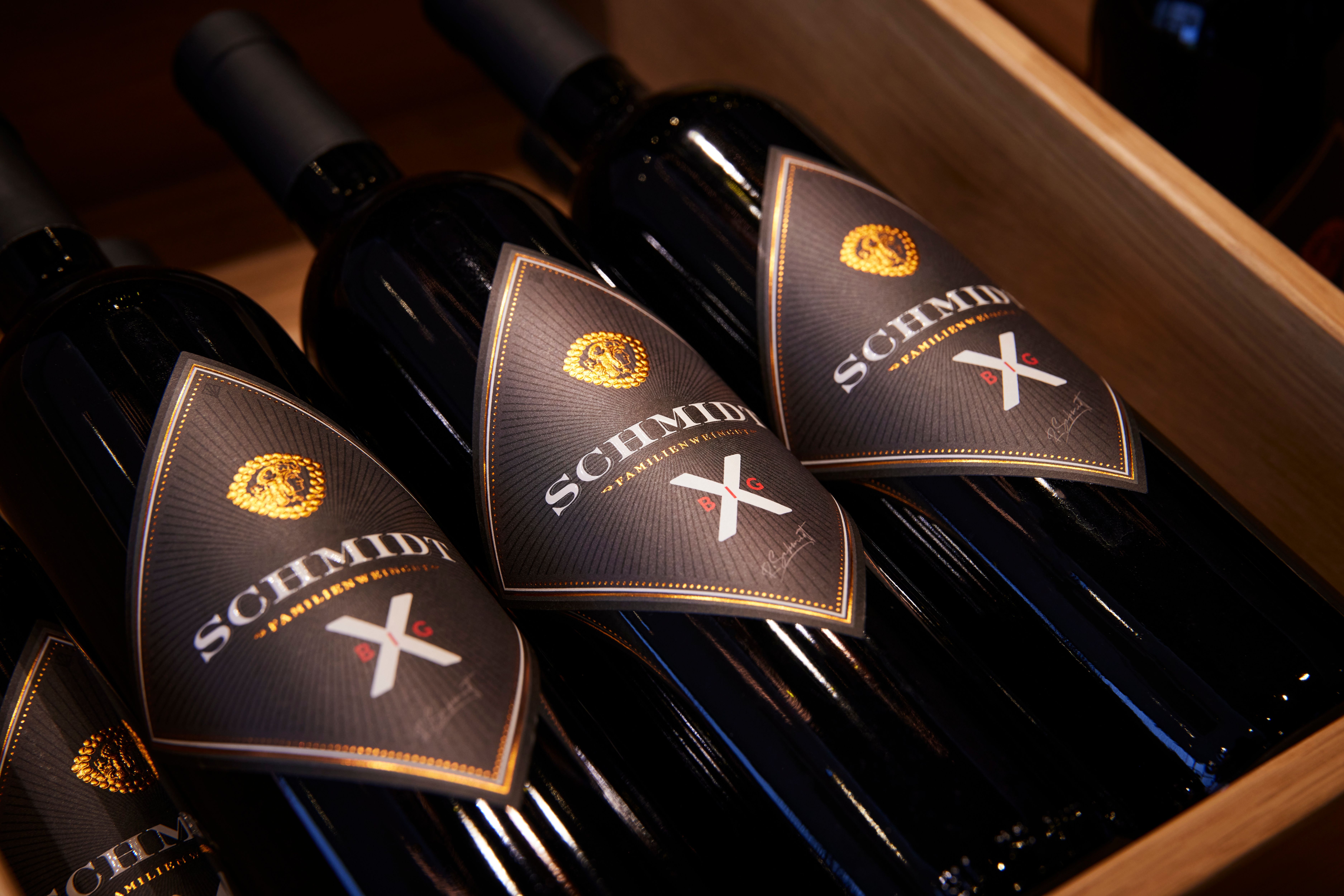 Drei Weinflaschen der Marke Schmidt in einer Holzkiste.