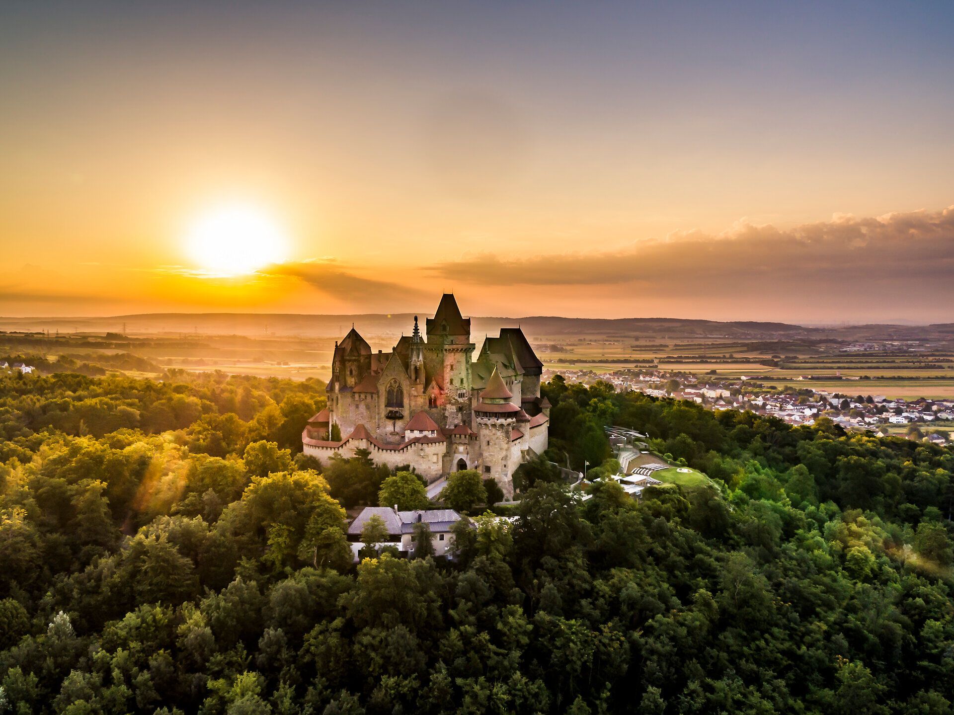 Die majestätische Burg Kreuzenstein thront über der malerischen Landschaft und bietet einen atemberaubenden Blick auf die sanften Hügel des Weinviertels. Bei Sonnenuntergang erstrahlt die Burg in warmen Farben und lädt Besucher ein, in die Geschichte und die Schönheit dieser Region einzutauchen.