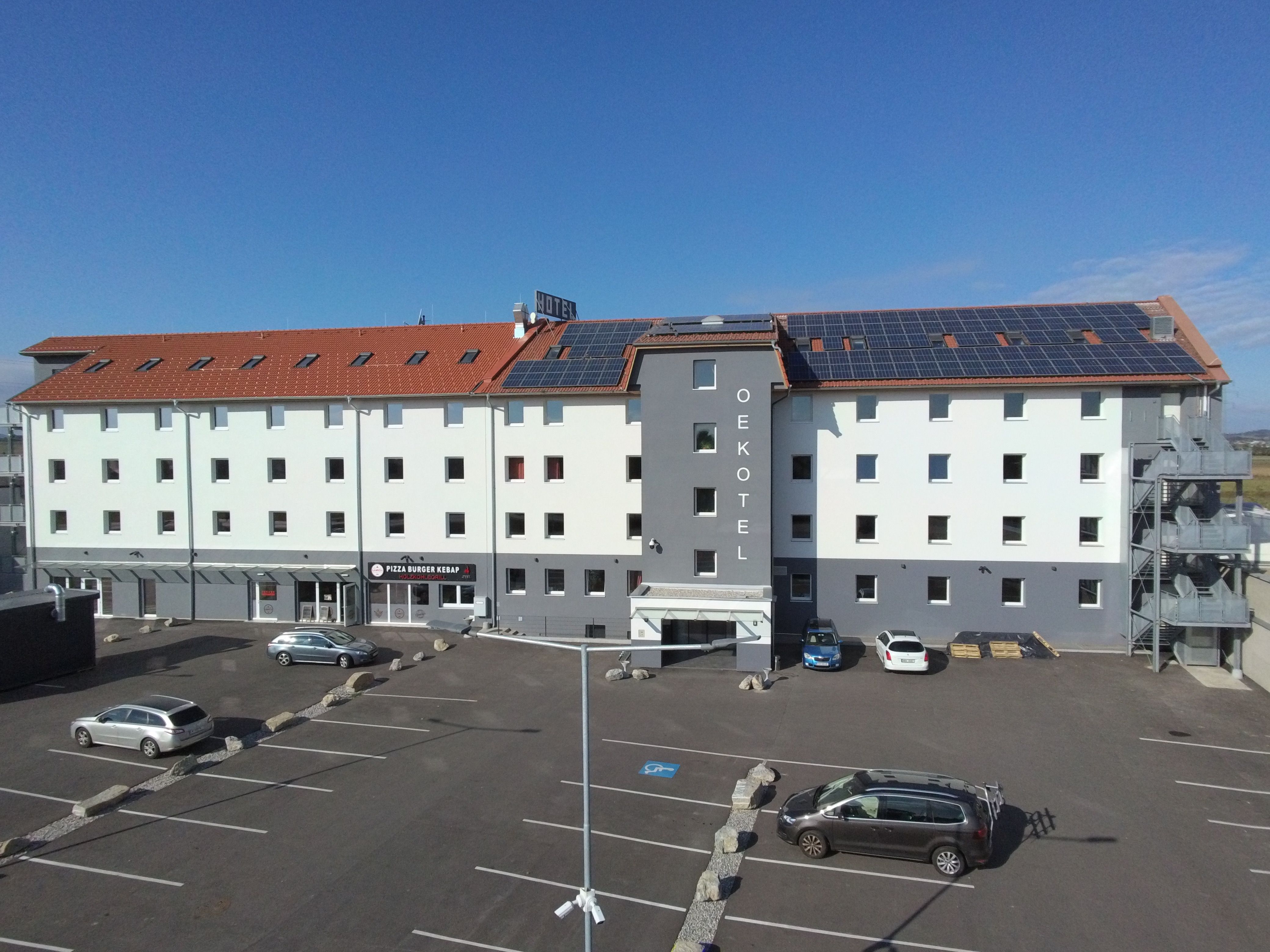 OEKOTEL Föhrenhain with solar panels on the roof and parking lot in front.