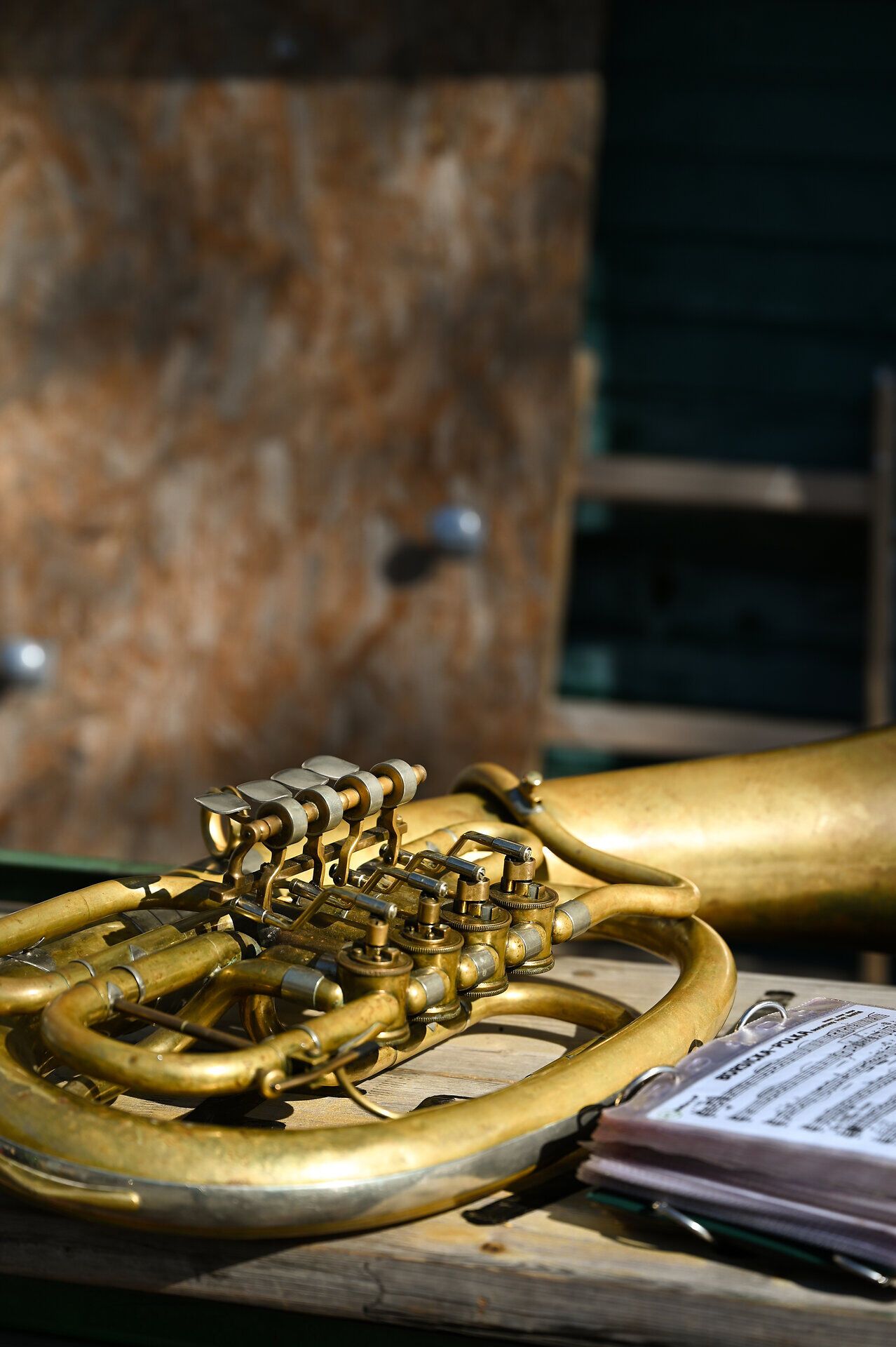 Ein goldglänzendes Blasinstrument ruht auf einem rustikalen Tisch, umgeben von Notenblättern, die die Melodien des Festes versprechen. Die warme Sonne taucht die Szene in ein sanftes Licht und lädt dazu ein, die Klänge der Musik und die Aromen des Weins zu genießen. Hier, wo Kunst und Kultur aufeinandertreffen, entsteht eine unvergessliche Atmosphäre.