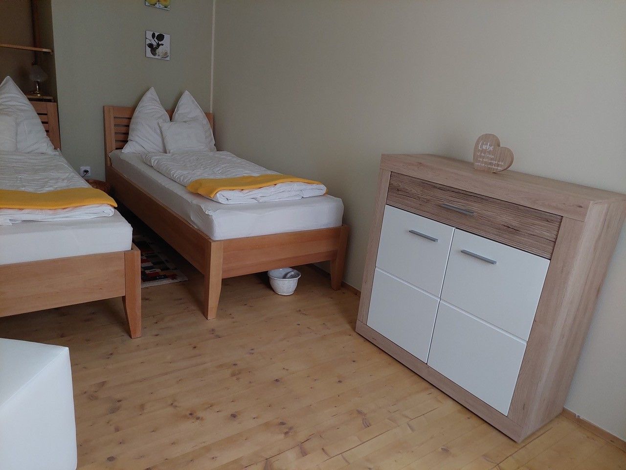 Zweibettzimmer mit zwei Einzelbetten, Holzboden und Kommode.