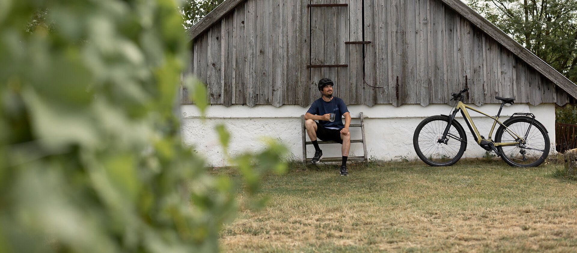 In der malerischen Umgebung von Pillersdorf lädt eine ruhige Bank zum Verweilen ein. Umgeben von sanften Hügeln und üppigem Grün, genießen Radfahrer die friedliche Atmosphäre und die Schönheit der Natur. Die charmante Holzhütte im Hintergrund erzählt von der traditionellen Weinbaukultur der Region.