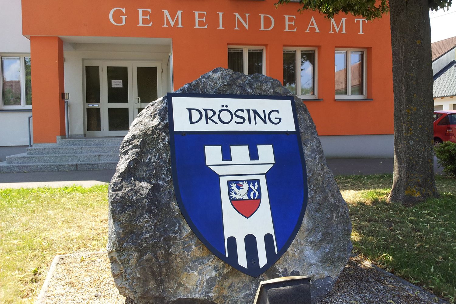 Eingang des Gemeindeamts Drösing mit Wappen auf einem Stein.