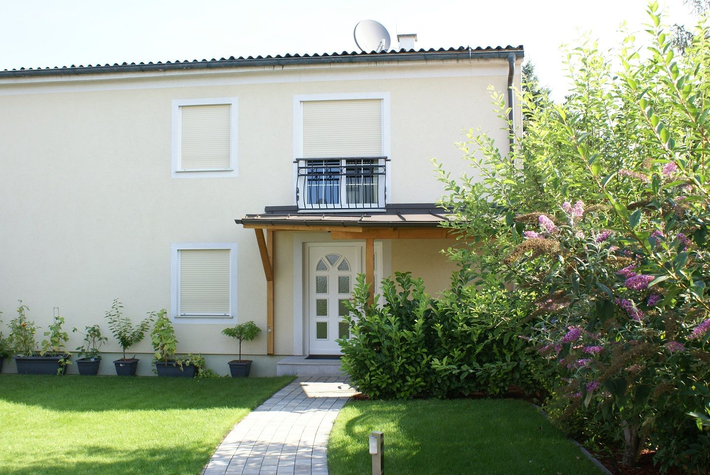 Außenansicht eines zweistöckigen Hauses mit Garten und Pflanzen.