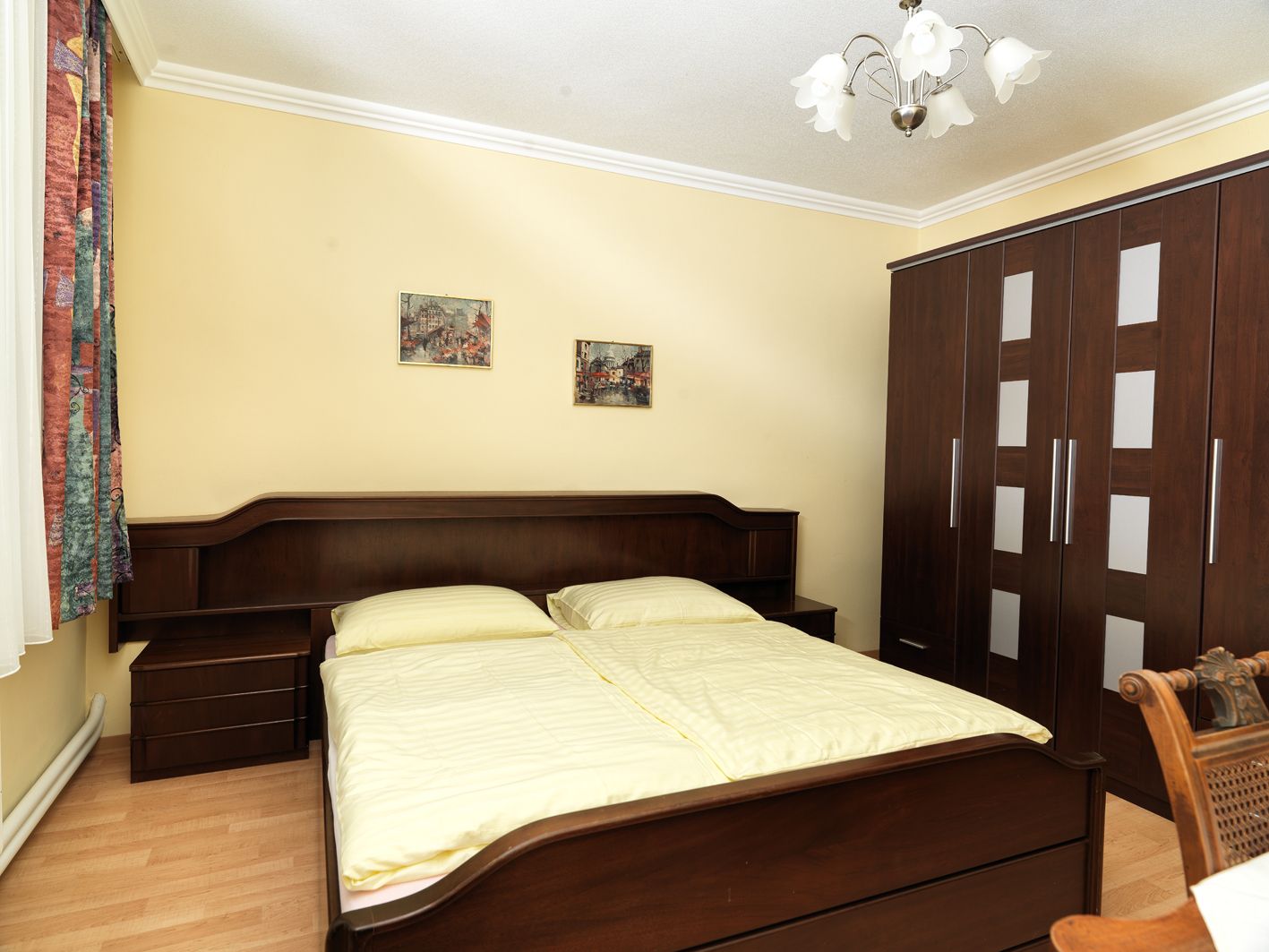 Ein gemütliches Schlafzimmer mit einem Doppelbett, einem großen Kleiderschrank und zwei Bildern an der Wand.