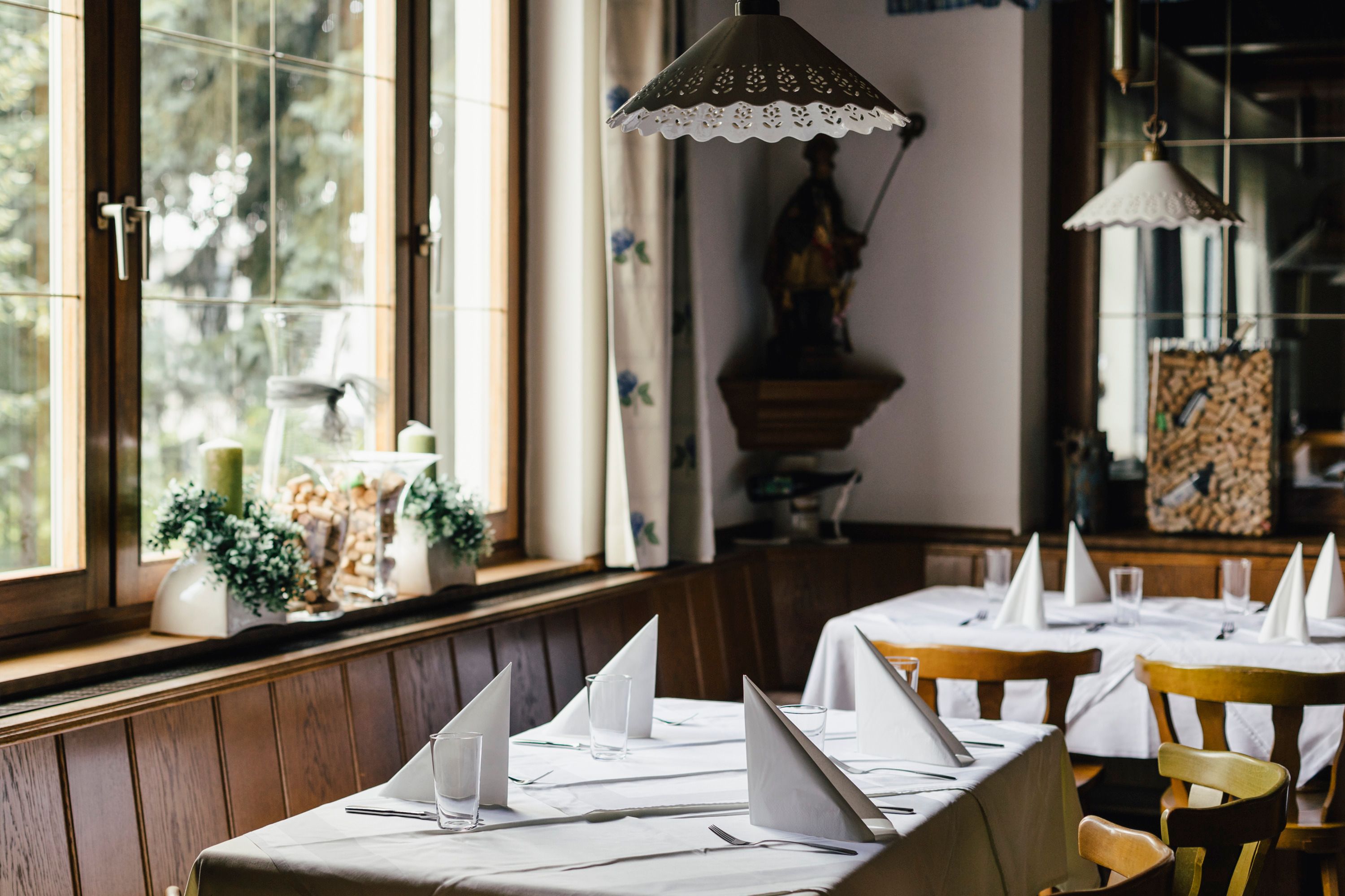 Innenansicht eines gemütlichen Restaurants mit gedeckten Tischen und Holzstühlen.