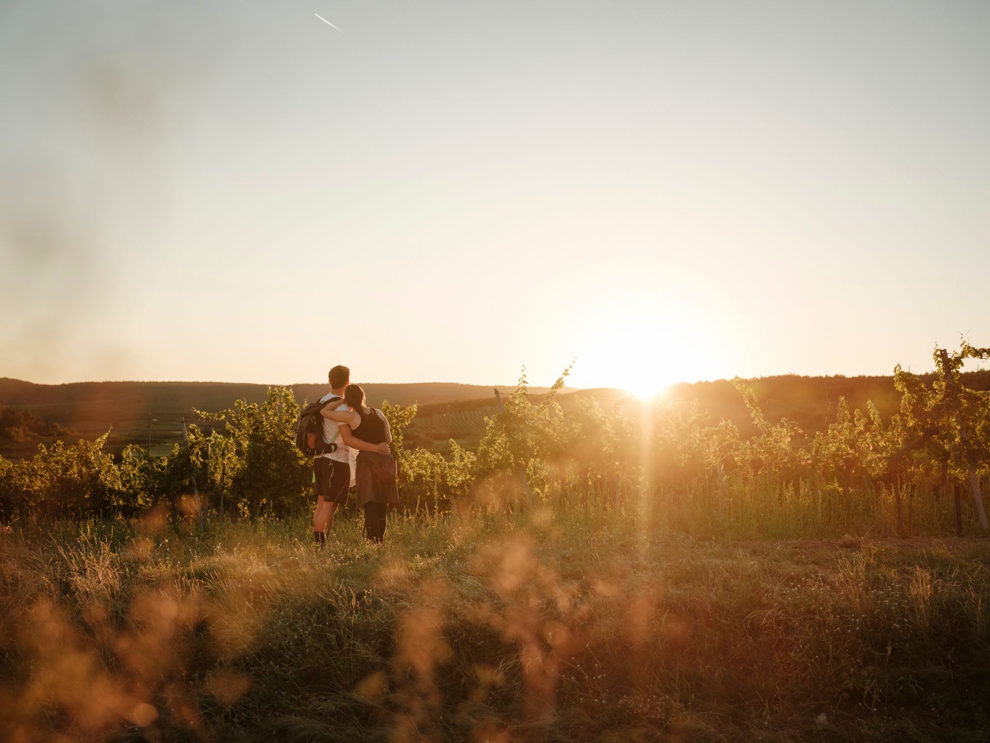 Ein Pärchen in Wanderkleidung steht in der Weinviertler Landschaft und genießt den Ausblick.