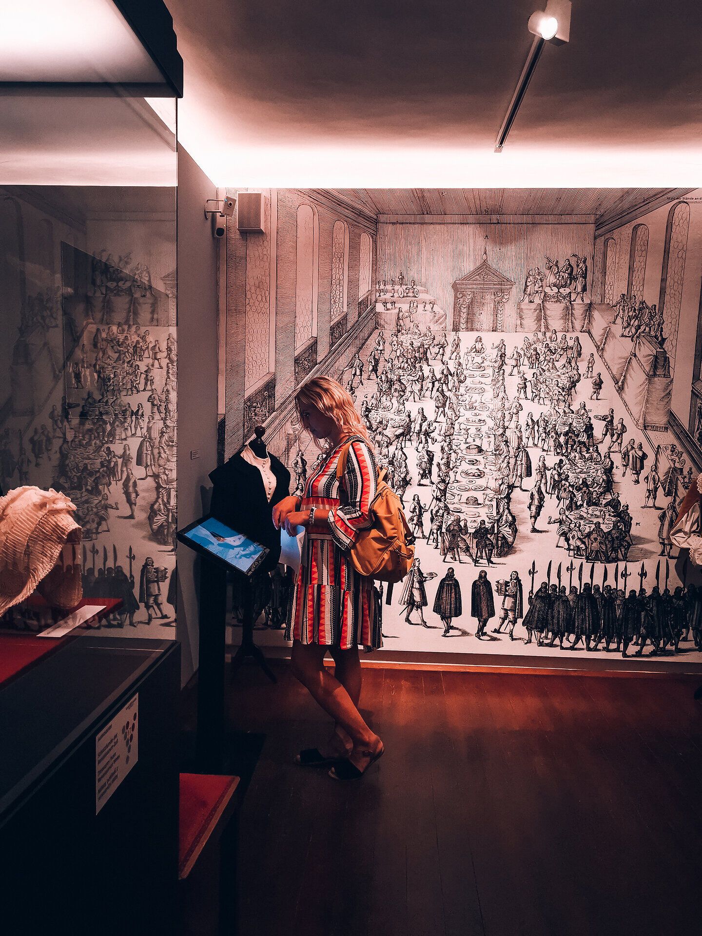 Inmitten der beeindruckenden Kulisse des Vinoversums erkundet eine Besucherin die faszinierende Welt des Weins. Die kunstvollen Wandmalereien und die liebevoll gestalteten Ausstellungsstücke laden dazu ein, in die Geschichte und Kultur des Weinbaus einzutauchen. Hier wird der Genuss von Wein zu einem unvergesslichen Erlebnis.