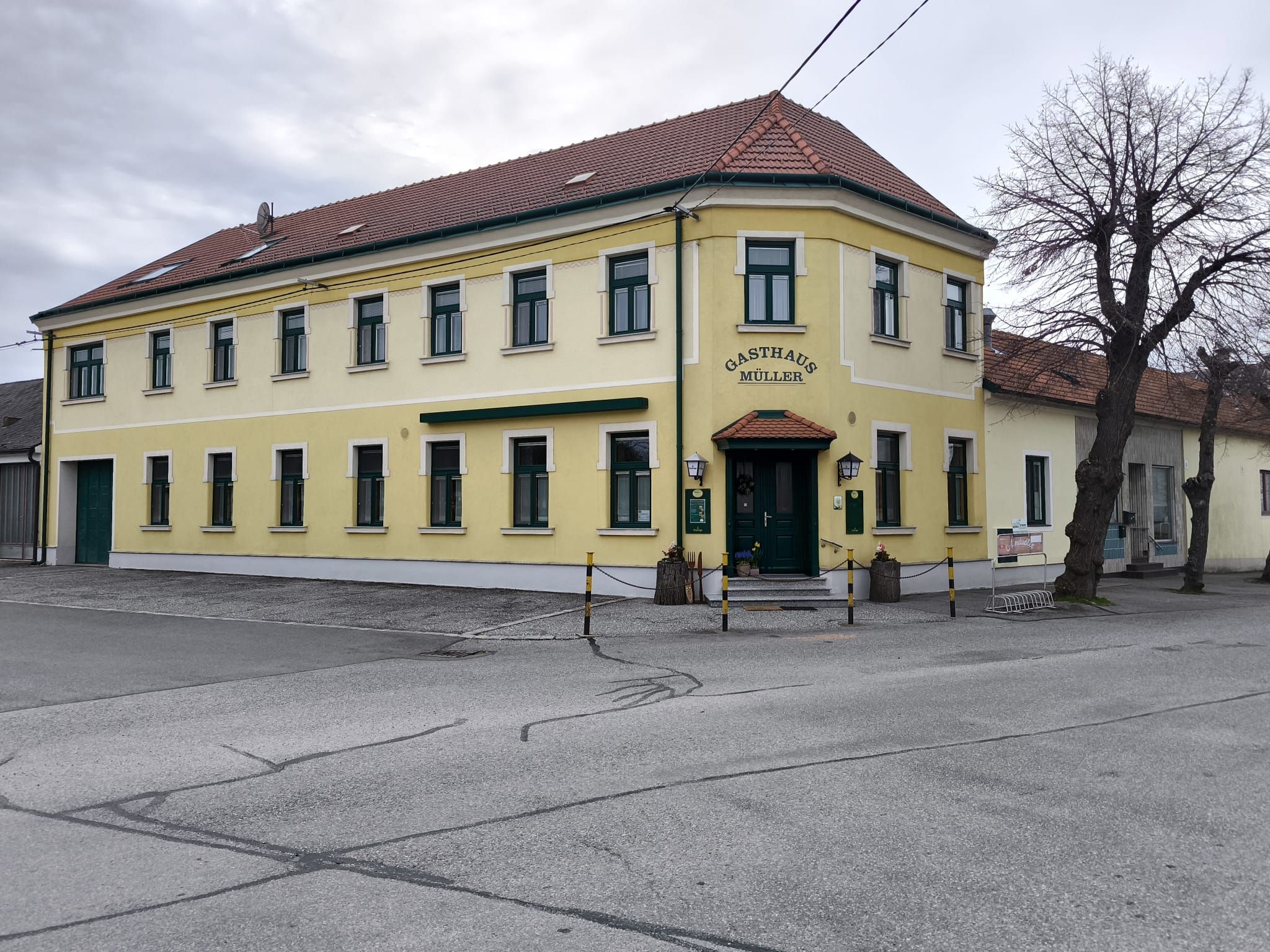 Gelbes zweistöckiges Gebäude mit der Aufschrift 'Gasthaus Müller'.