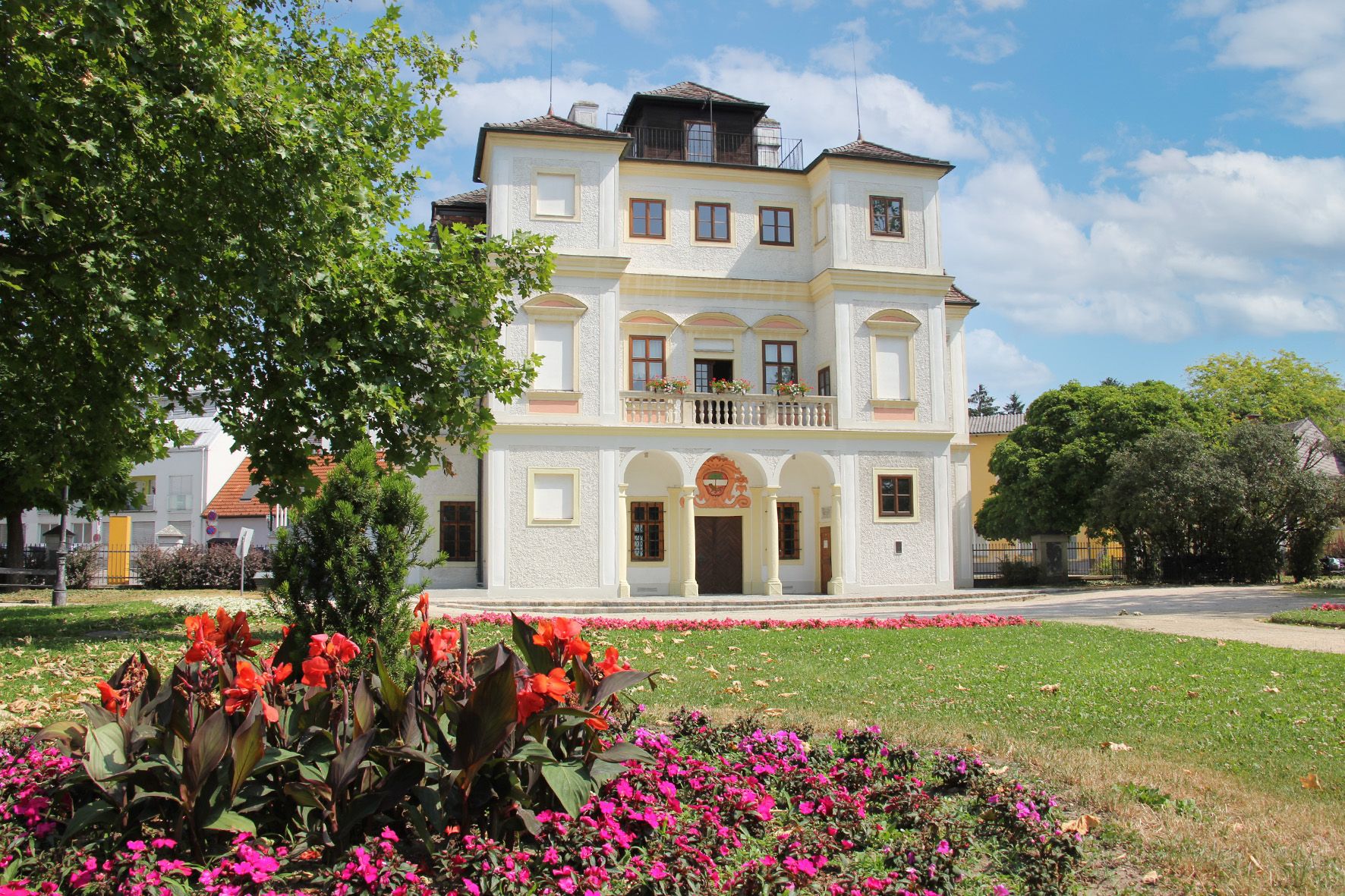 Das Belvedereschlössl in Stockerau mit blühenden Blumen im Vordergrund.