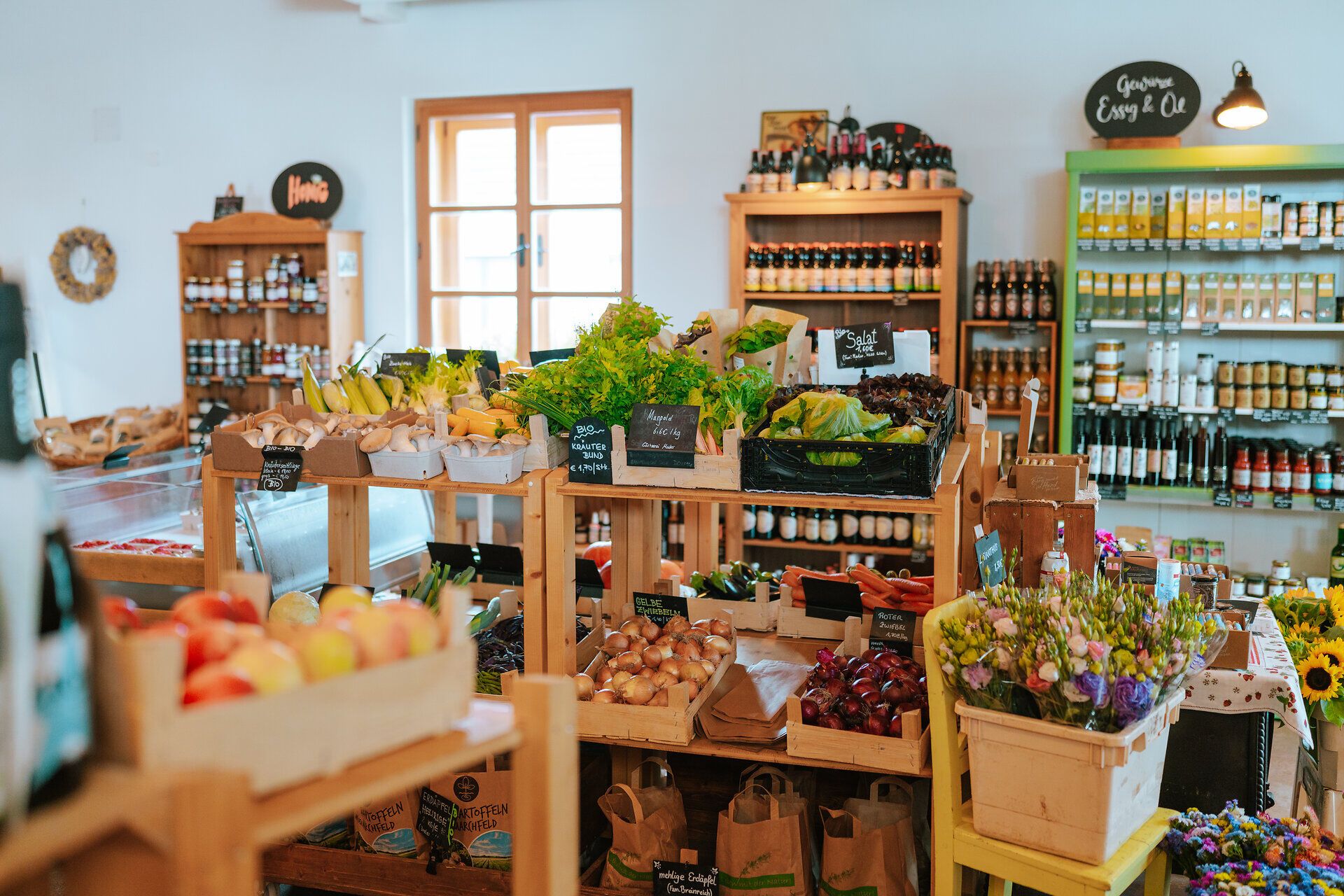 In einem einladenden Hofladen strahlen frische, bunte Gemüse und Obstsorten um die Wette. Die Regale sind liebevoll gefüllt mit regionalen Köstlichkeiten, die den Duft des Landlebens verbreiten und zum Verweilen einladen.