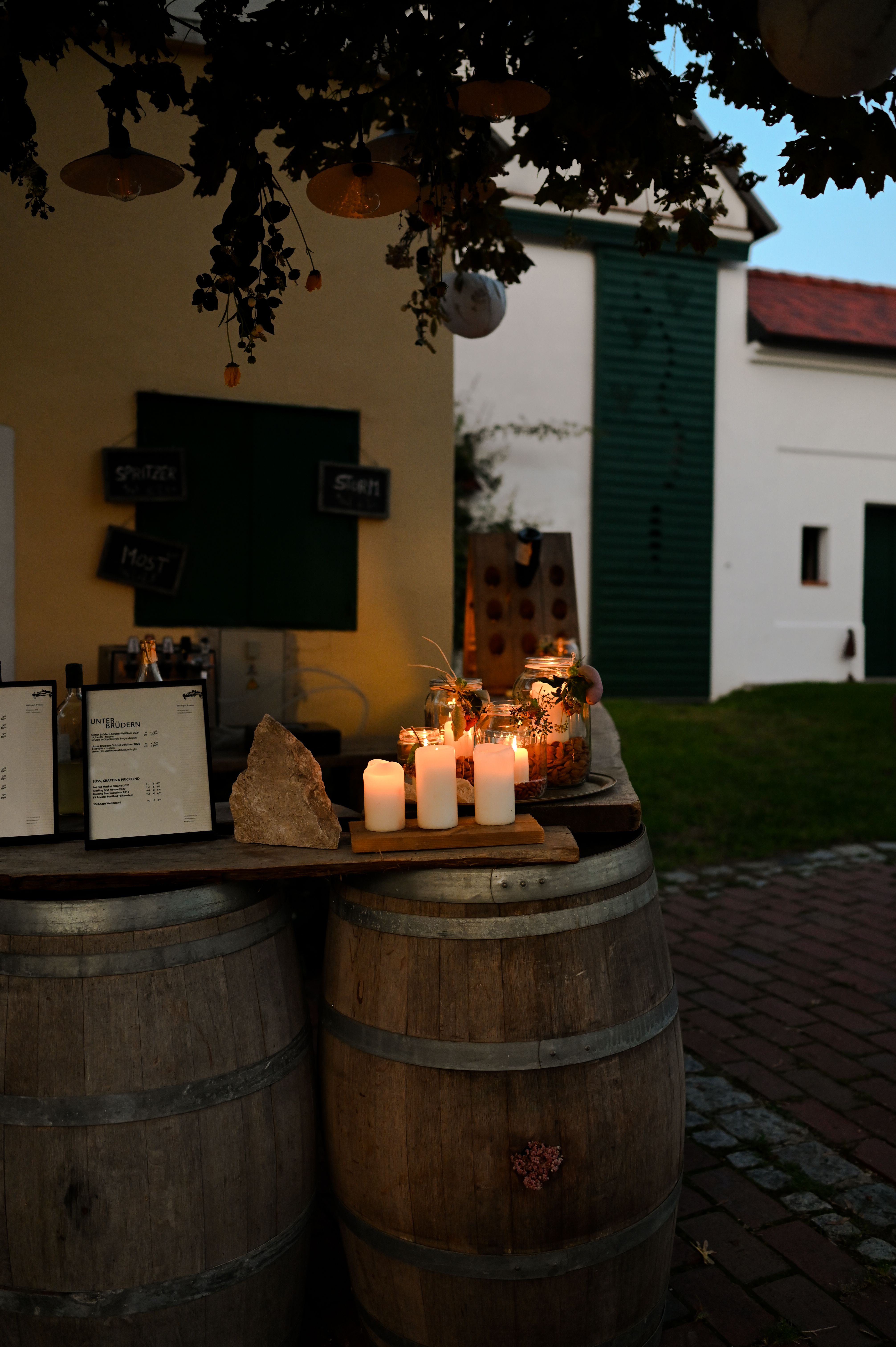 In einer romantischen Atmosphäre erleuchten Kerzen die rustikalen Holzfässer, während der Duft von Wein und frischen Kräutern in der Luft liegt. Besucher genießen die harmonische Verbindung von Kunst und Kultur beim Kellergassenfest, umgeben von der malerischen Kulisse der Weinviertler Landschaft.