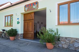 Eingang eines Gebäudes mit Holztür und Pflanzen in Töpfen.