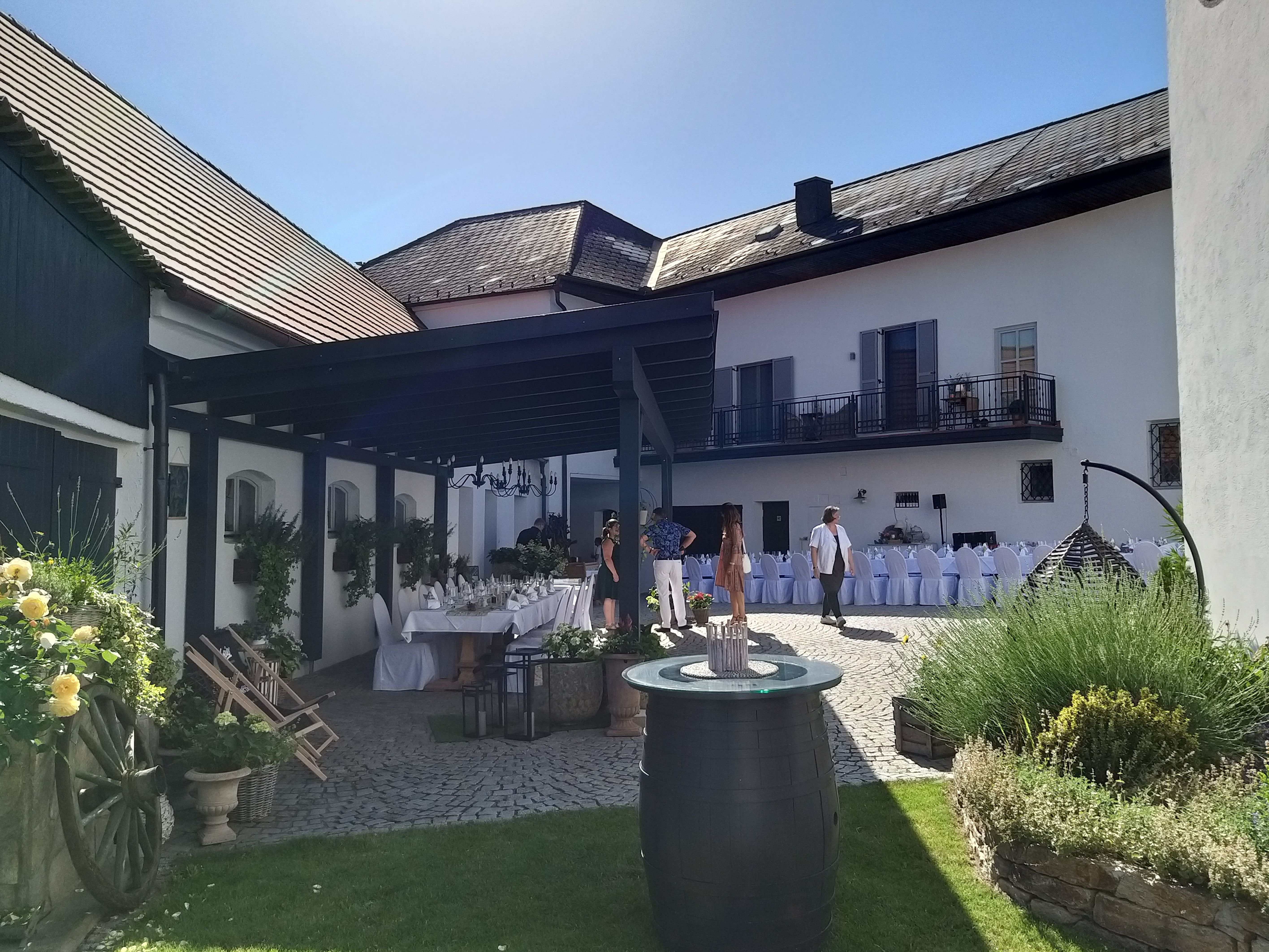 Innenhof mit gedeckten Tischen und dekorativen Pflanzen, sonniger Tag.