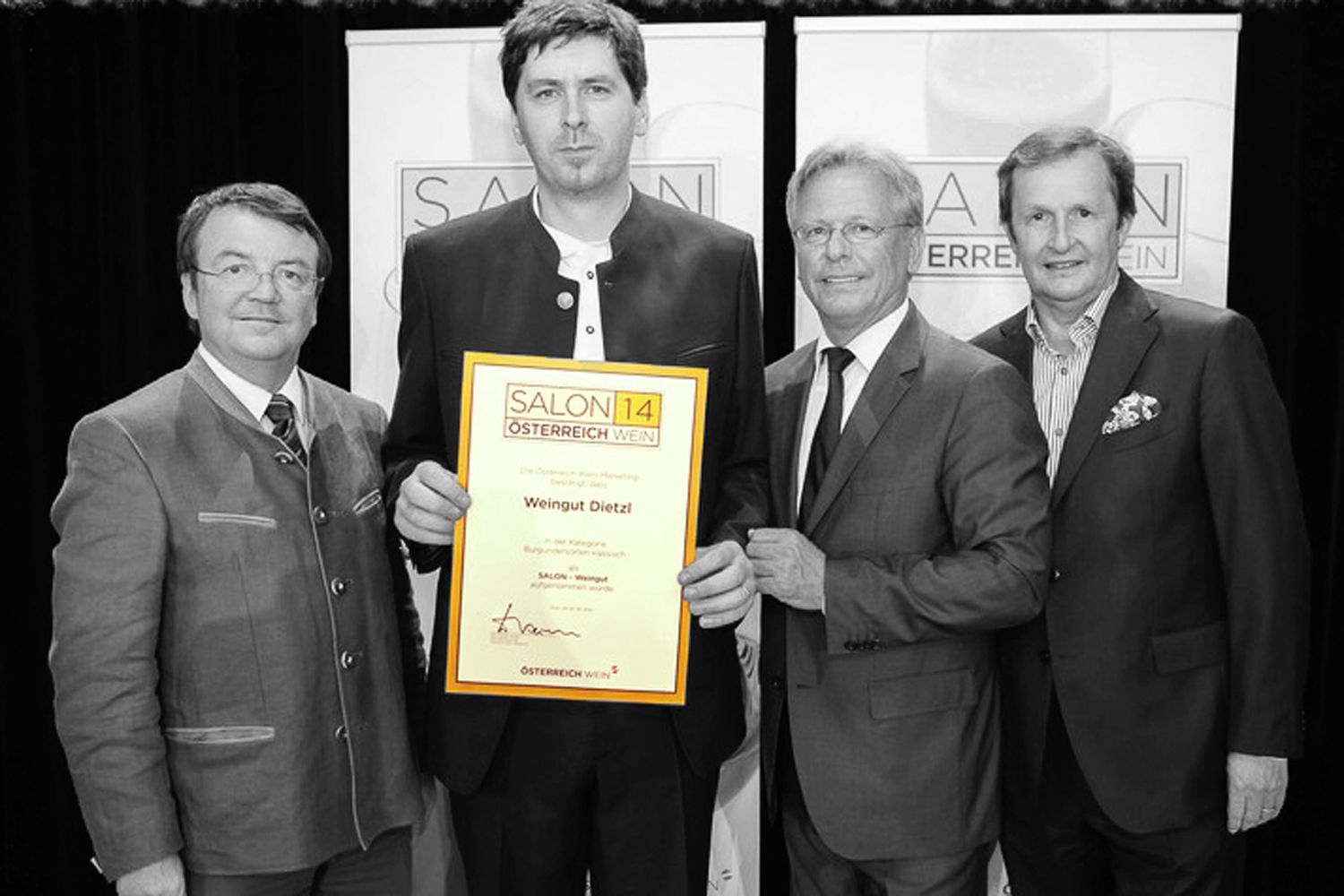 Vier Männer in Anzügen halten eine Auszeichnung mit der Aufschrift 'Salon 14 Österreich Wein' in die Kamera.