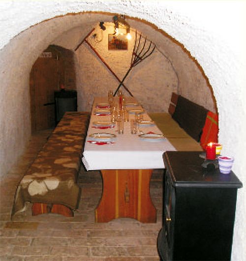 Gemütlicher Weinkeller mit gedecktem Tisch und rustikaler Einrichtung.