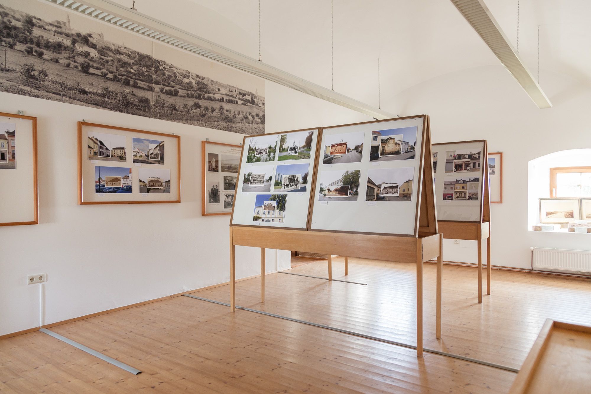 Innenansicht eines Museumsraums mit Fototafeln und historischen Bildern an den Wänden.